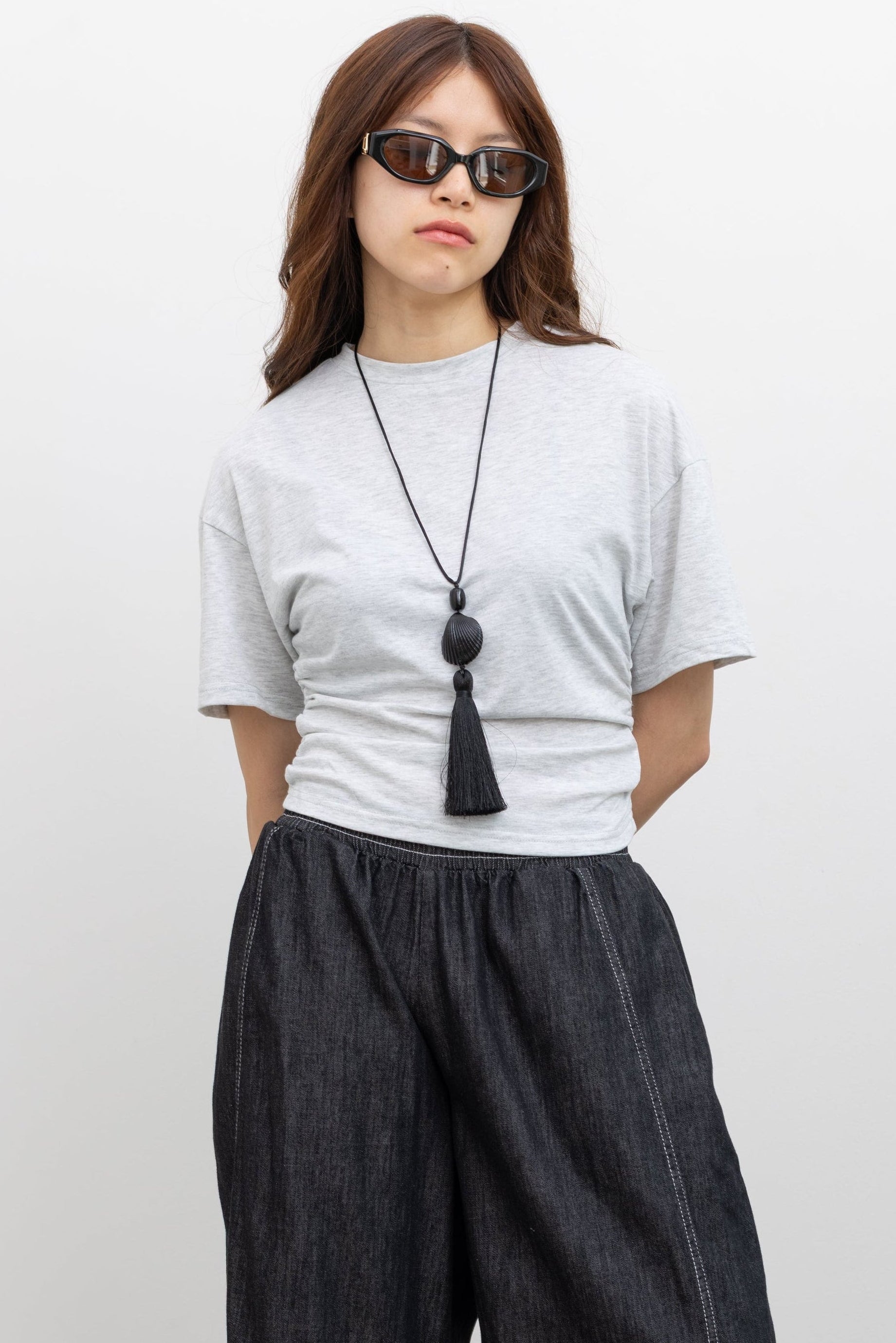 Front view of a woman wearing elevated essential basic t-shirt in a Collective label light gray batwing sleeve cinched waist tee featuring a slim-fit, sculptural side-ruching, relaxed drop shoulders and a clean crew neck. Crafted from a soft, fluid stretch blend, it pairs effortlessly Alas Eius label black contrast stitch barrel jeans at Alas Eius.