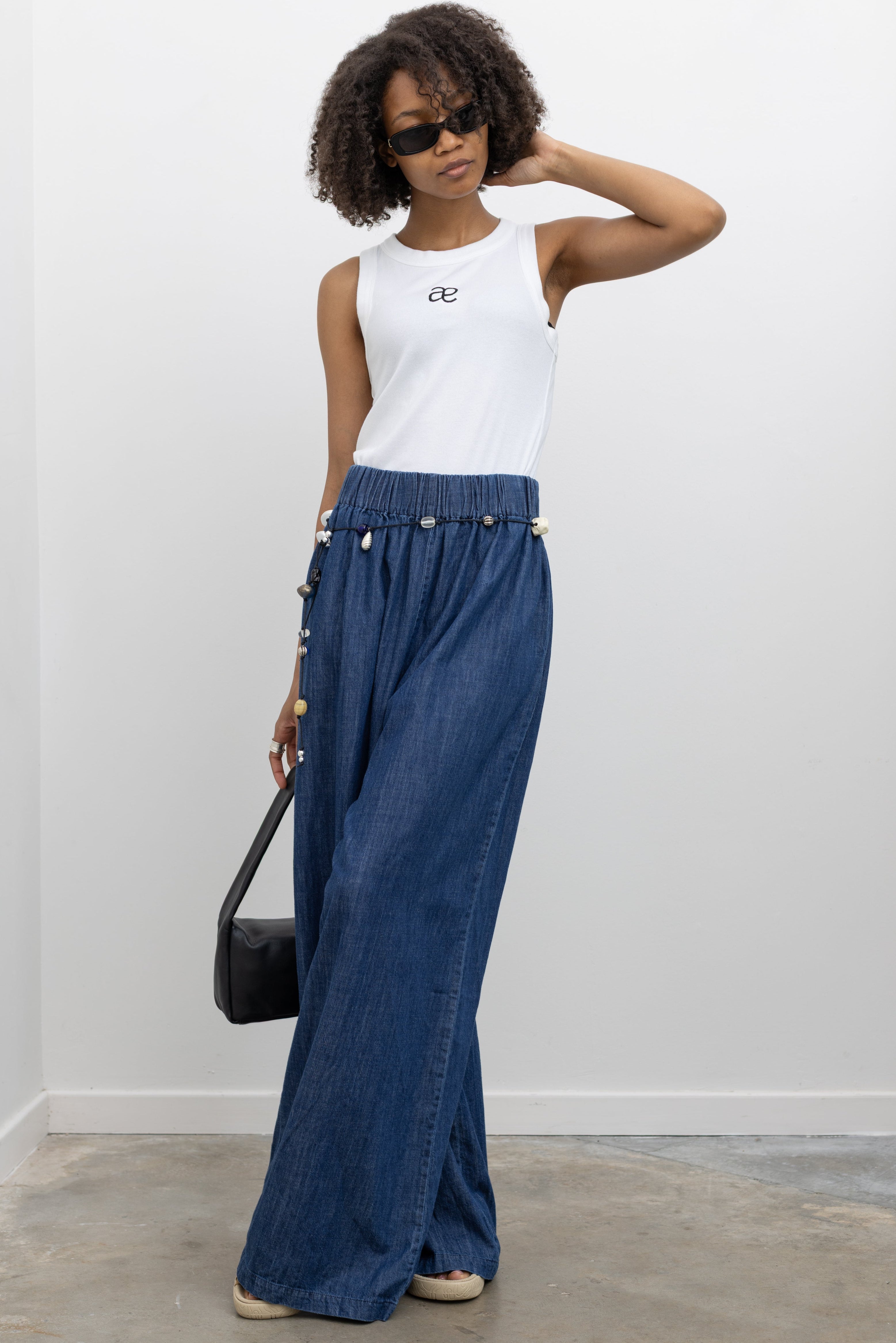 Model wearing summer fashion in the Collective blue wide-leg cotton pants with a relaxed fit, elastic waistband, and lightweight denim fabric at Alas Eius 