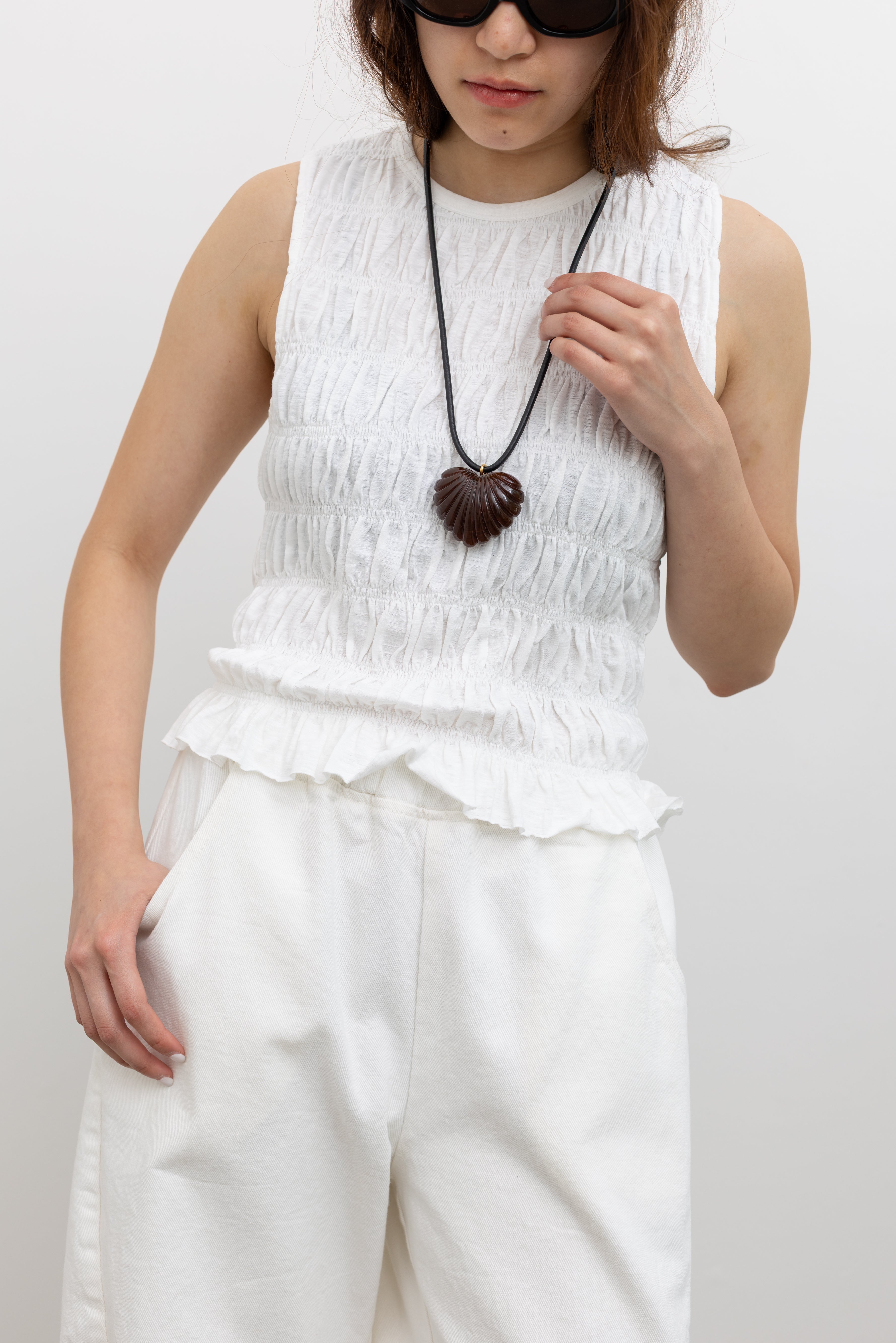 Collective Textured full-body smocked sleeveless top in 100% cotton with flounced hem detail paired with a Rachel Comey Shell-Inspired Heart Pendant Necklace at Alas Eius