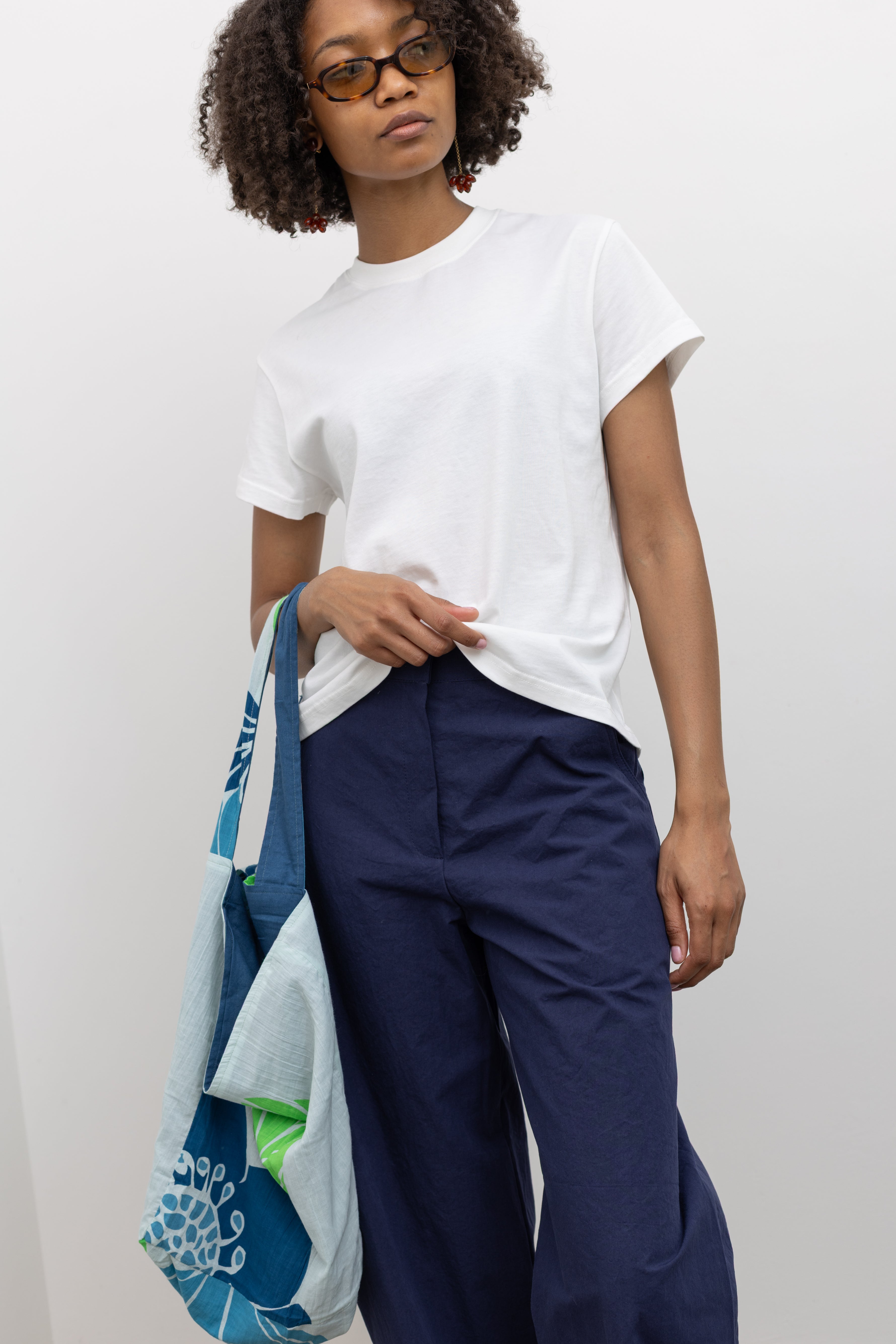 Elevated workwear fashion in Collective blue cotton barrel-leg high waisted pants with a relaxed curved fit and wide-leg silhouette paired with a white tee at Alas Eius.