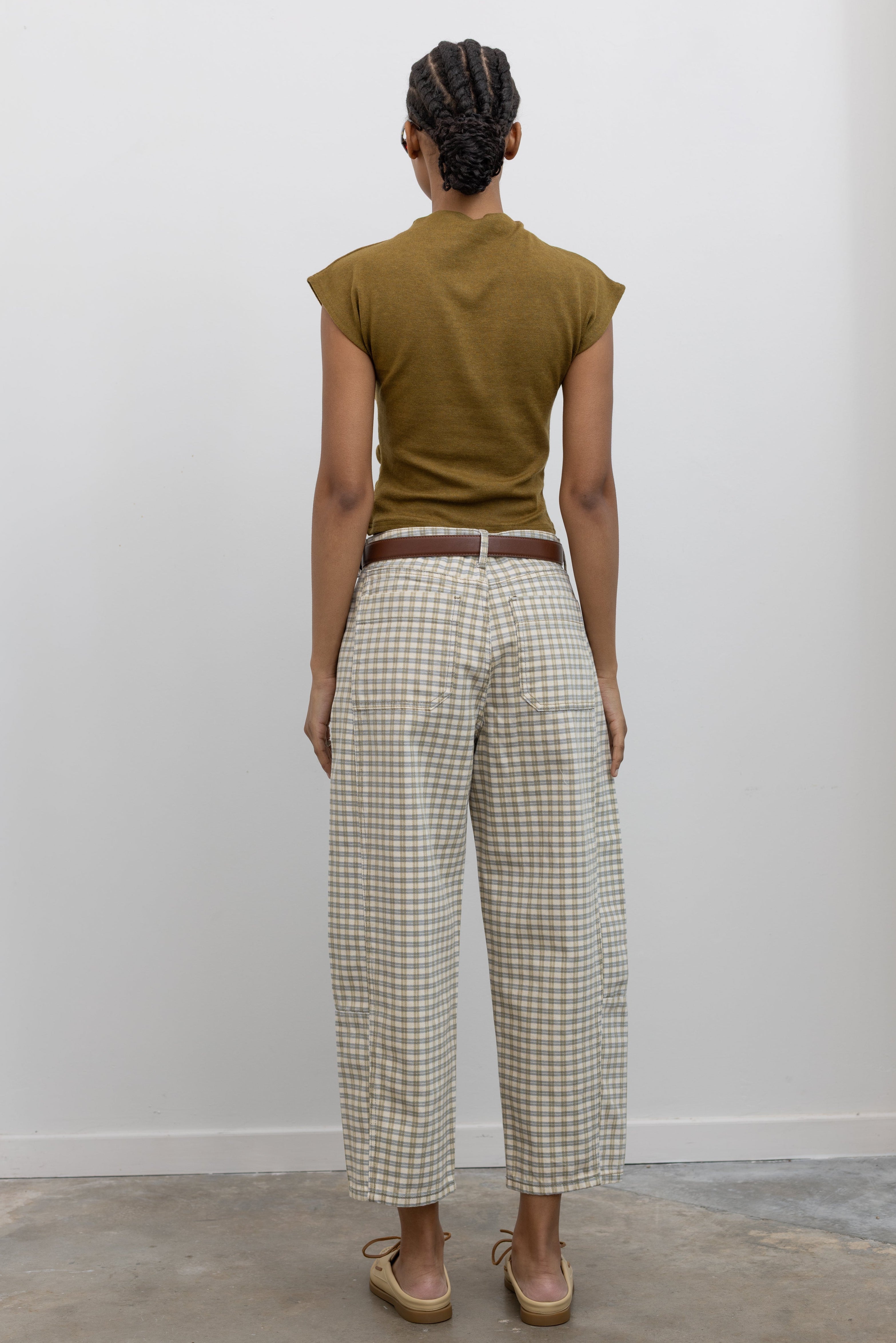 Back view of a woman standing wearing Spring fashion in a pair of Collective Olive Checkered Barrel Cropped Pants with a short sleeved top and beige leather shoes at Alas Eius