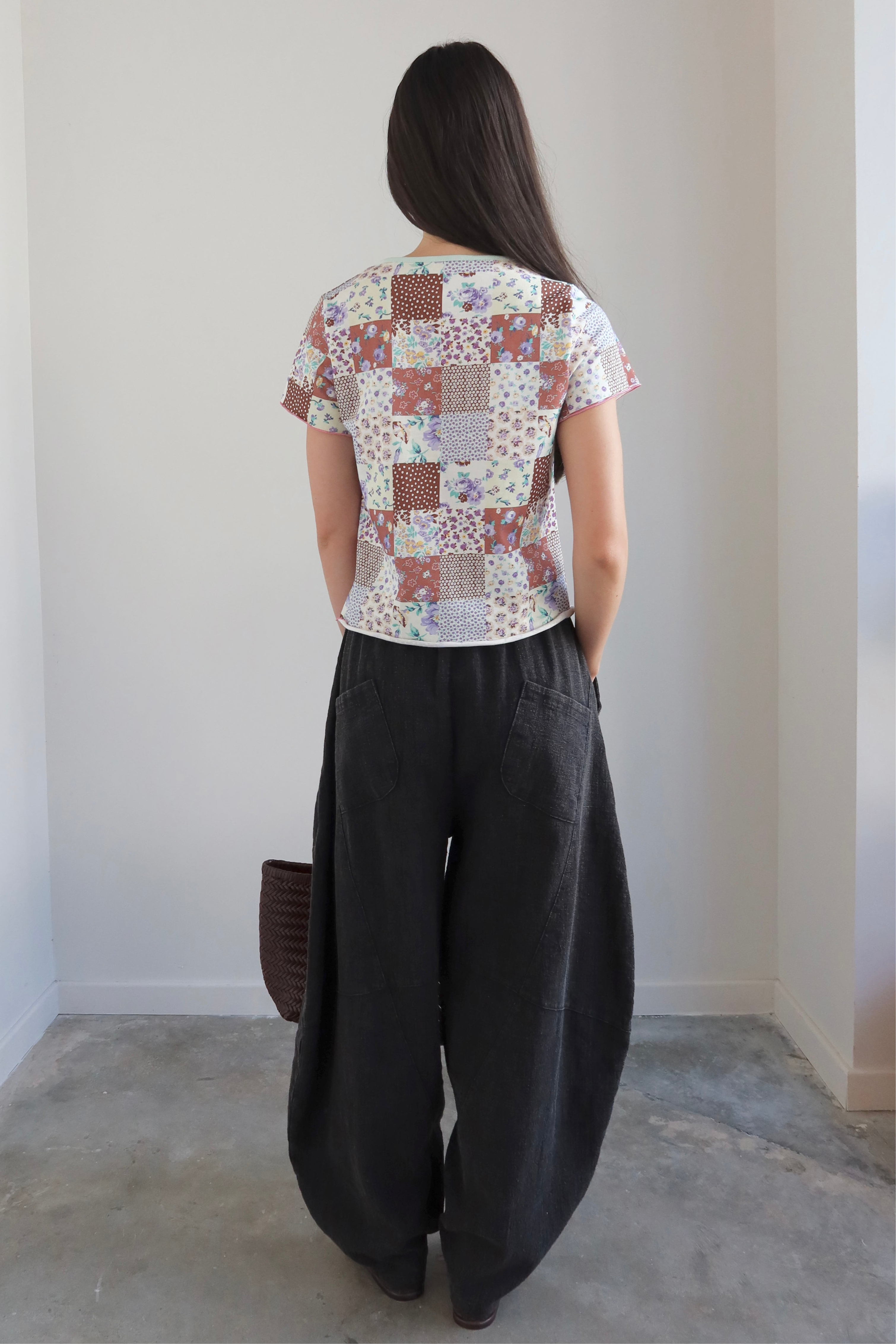 Full length front view of a Woman wearing a Collective Quilted Pattern Floral Tee Shirt  with oversized barrel leg pants at Alas Eius