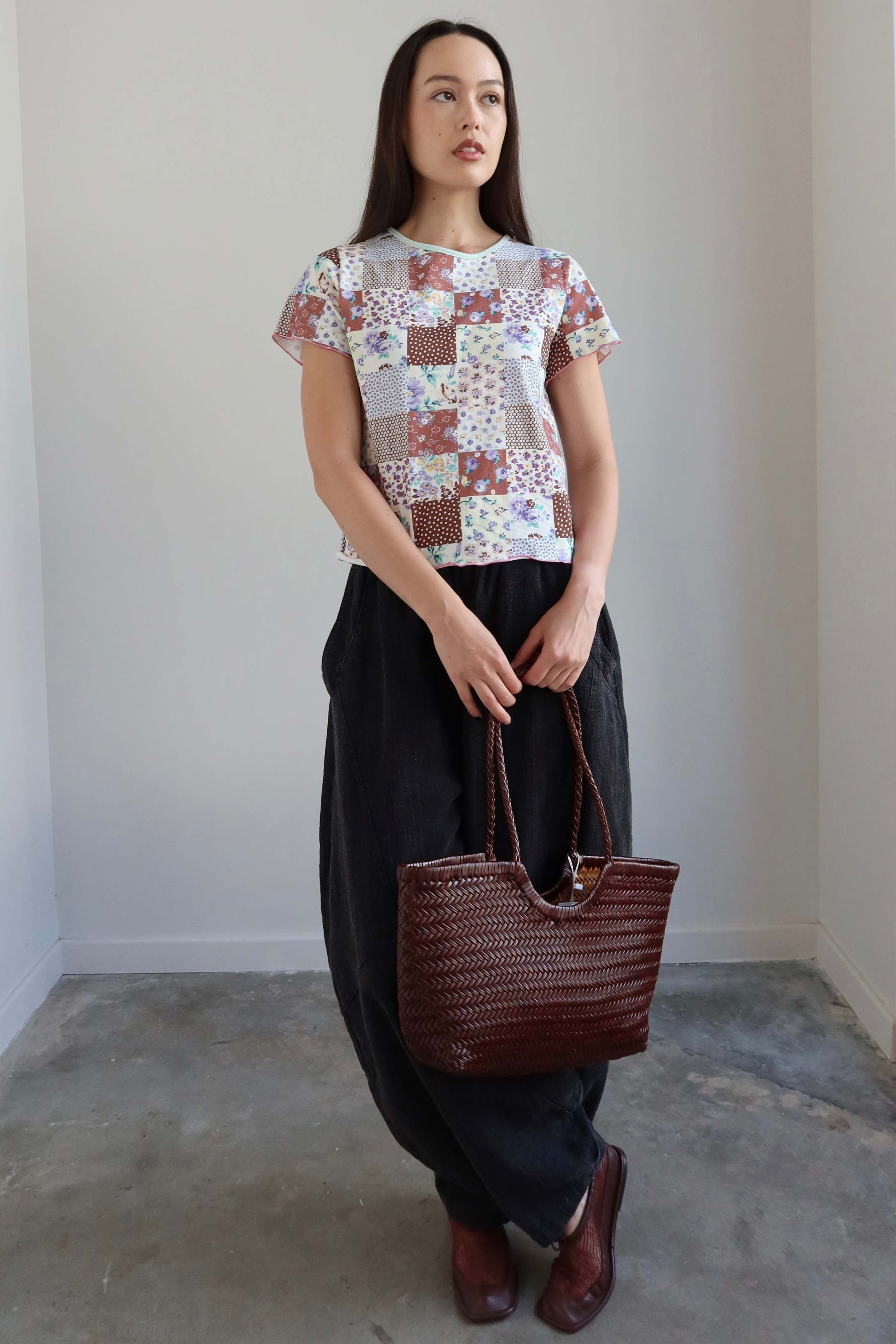 Full length front view of a Woman wearing a Collective Quilted Pattern Floral Tee Shirt  with oversized parachute pants at Alas Eius
