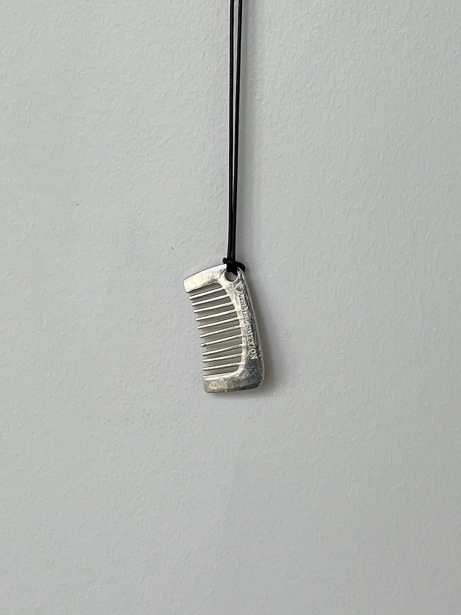 Close-up view of a Collective Brand Silver Comb Necklace On a Leather Cord at Alas Eius