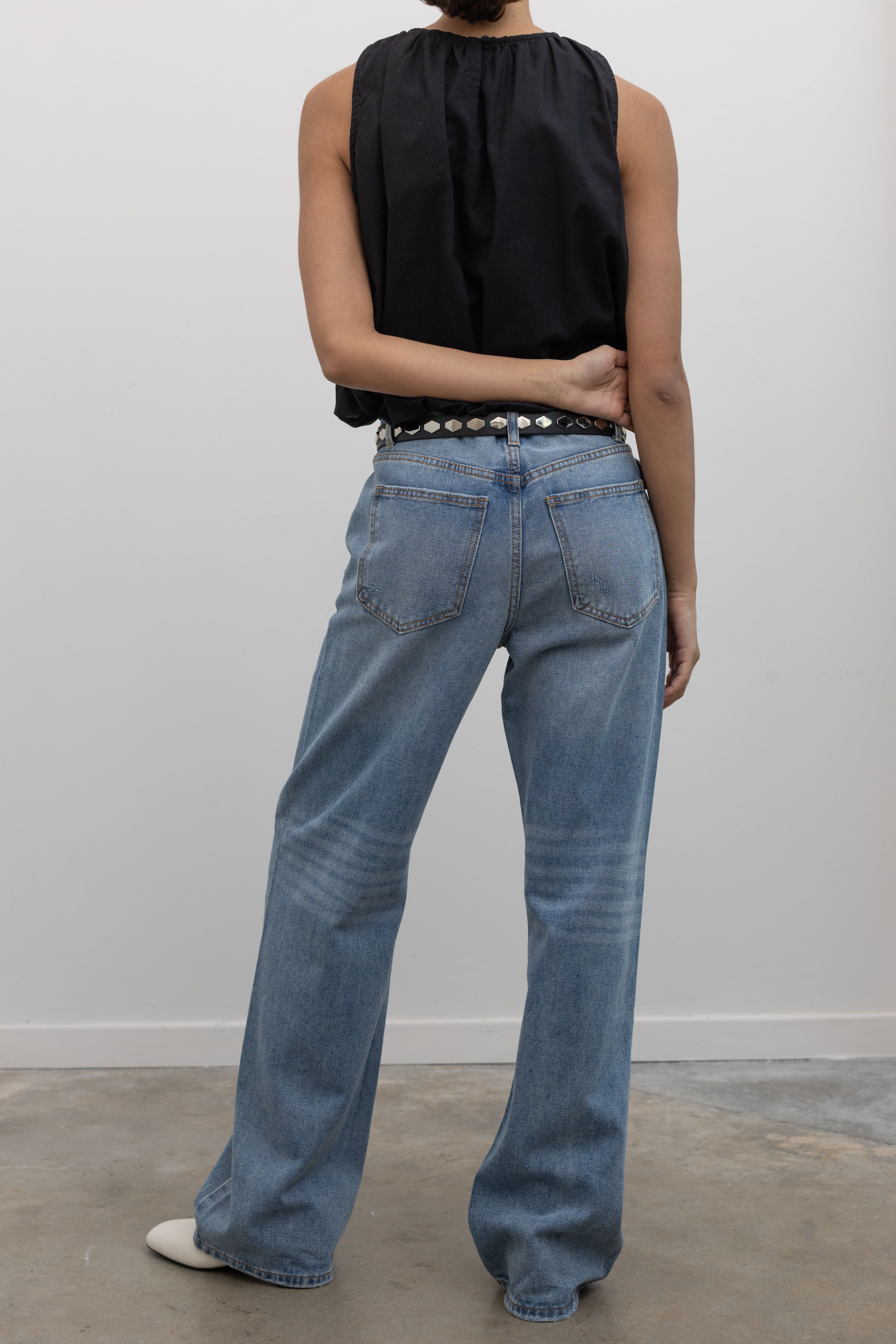 Back view of Woman standing wearing Spring fashion in a black gathered neck and balloon hem top with a pair of Collective Light Wash Slouchy Mid Rise Jeans at Alas Eius 