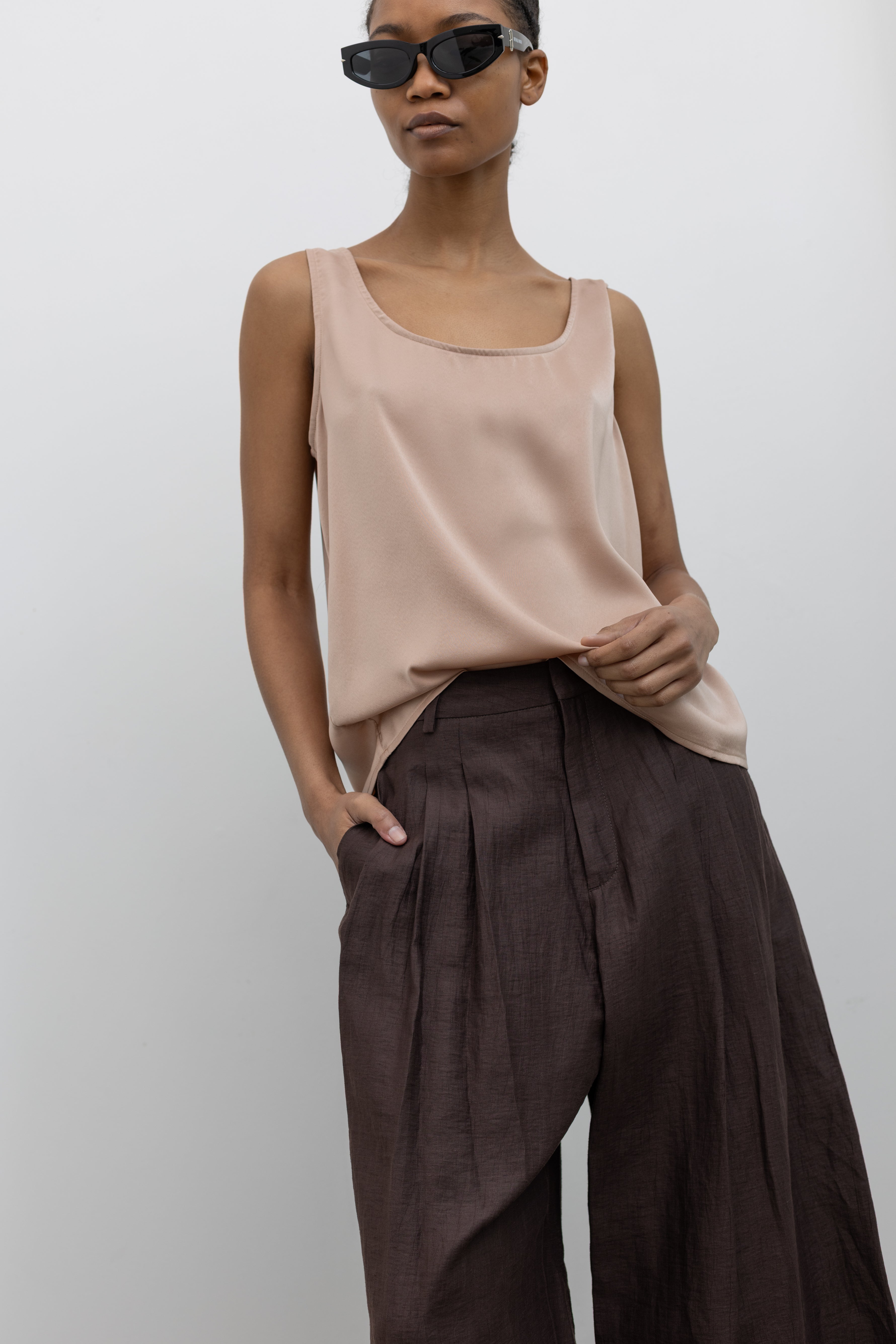 Woman wearing Spring fashion in a Collective brand solid beige satin tank top with a relaxed flowy fit paired with pleated trouser at Alas Eius.