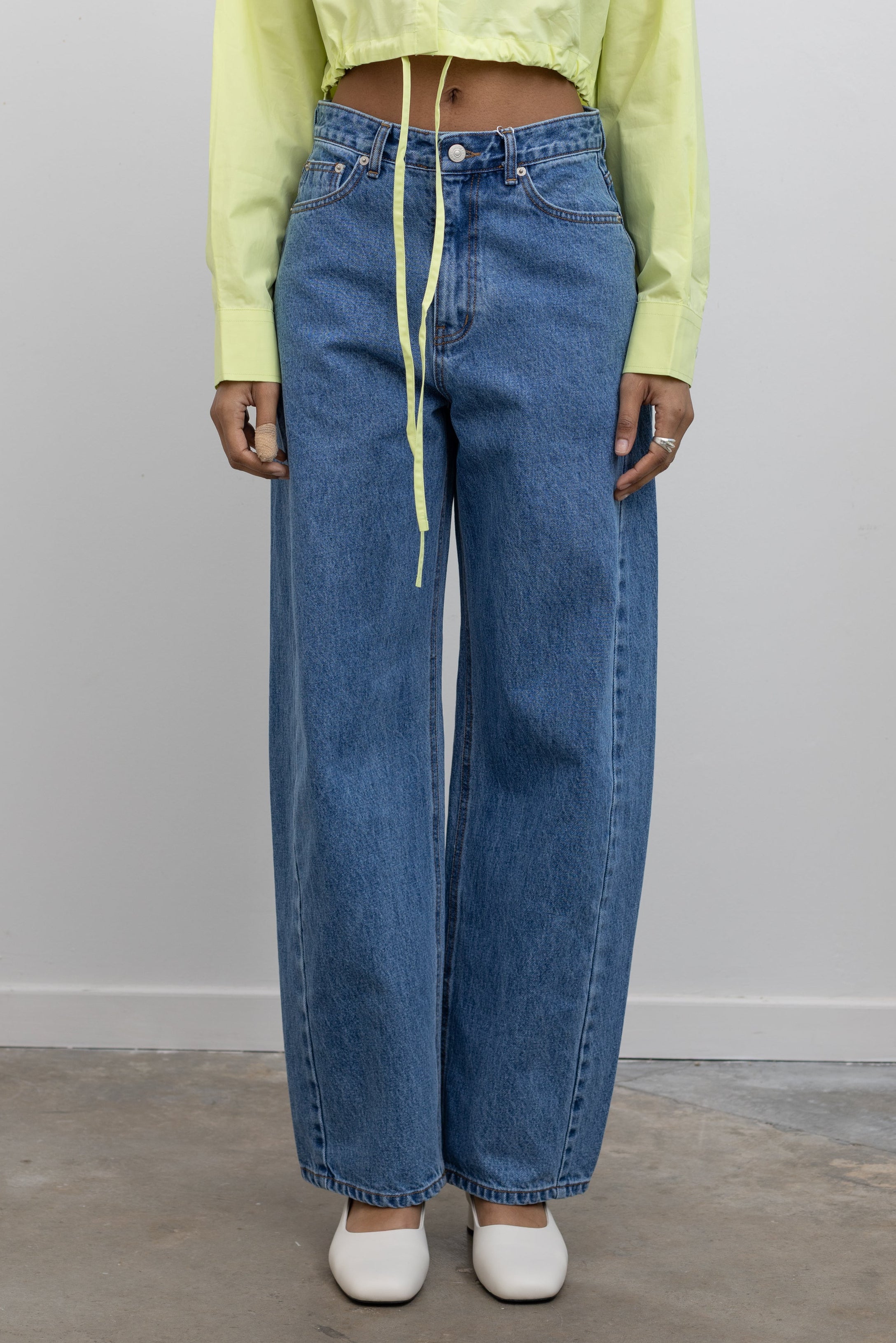 Front view of woman standing wearing Spring fashion in a pair of Collective Mid Rise Baggy Balloon Stone Washed Jeans and a yellow cropped shirt at Alas Eius