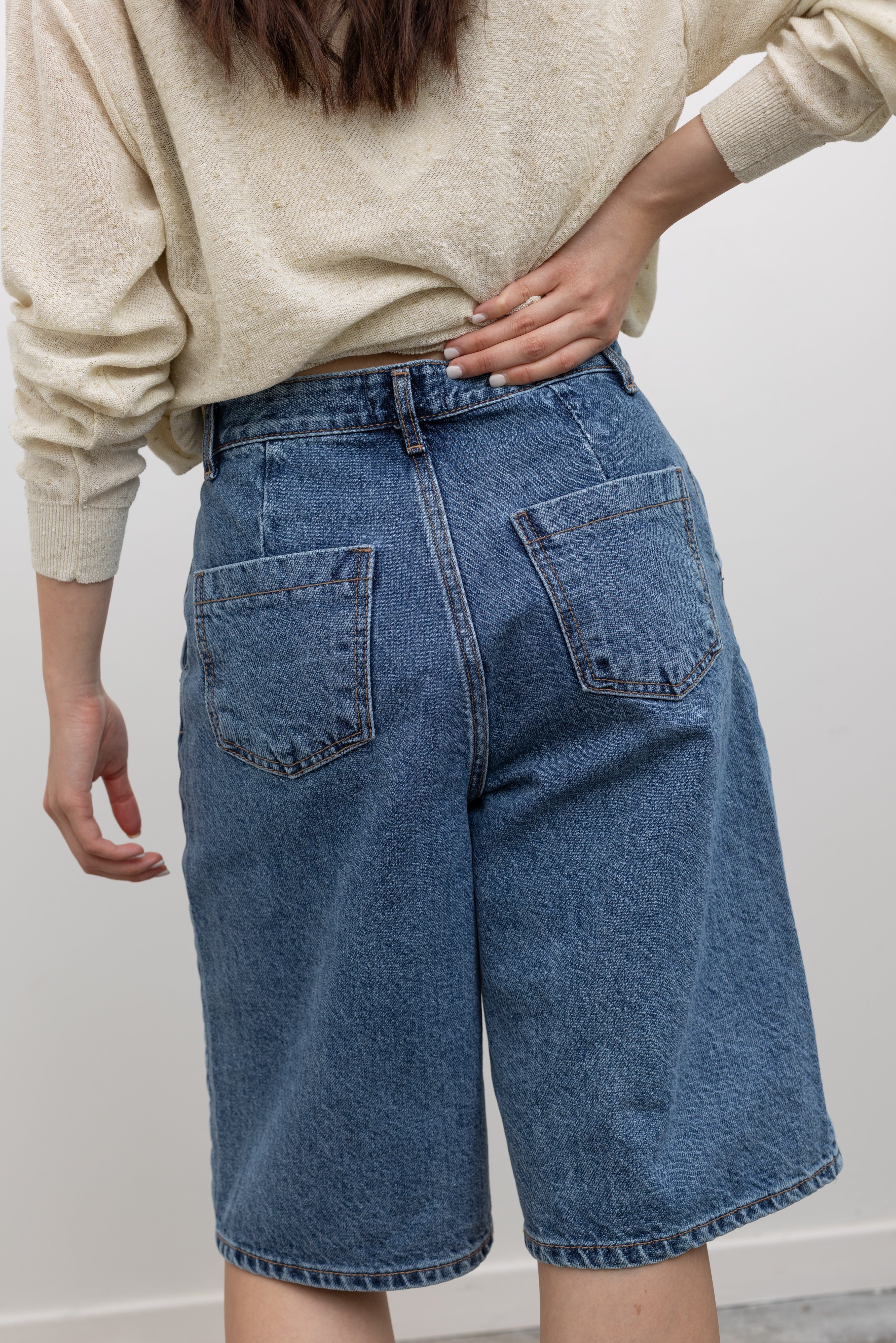 Model wearing womens knee length short in the Collective stone-washed light blue denim bermuda shorts with a mid-to-high rise, wide-leg silhouette, and knee-length design at Alas Eius.
