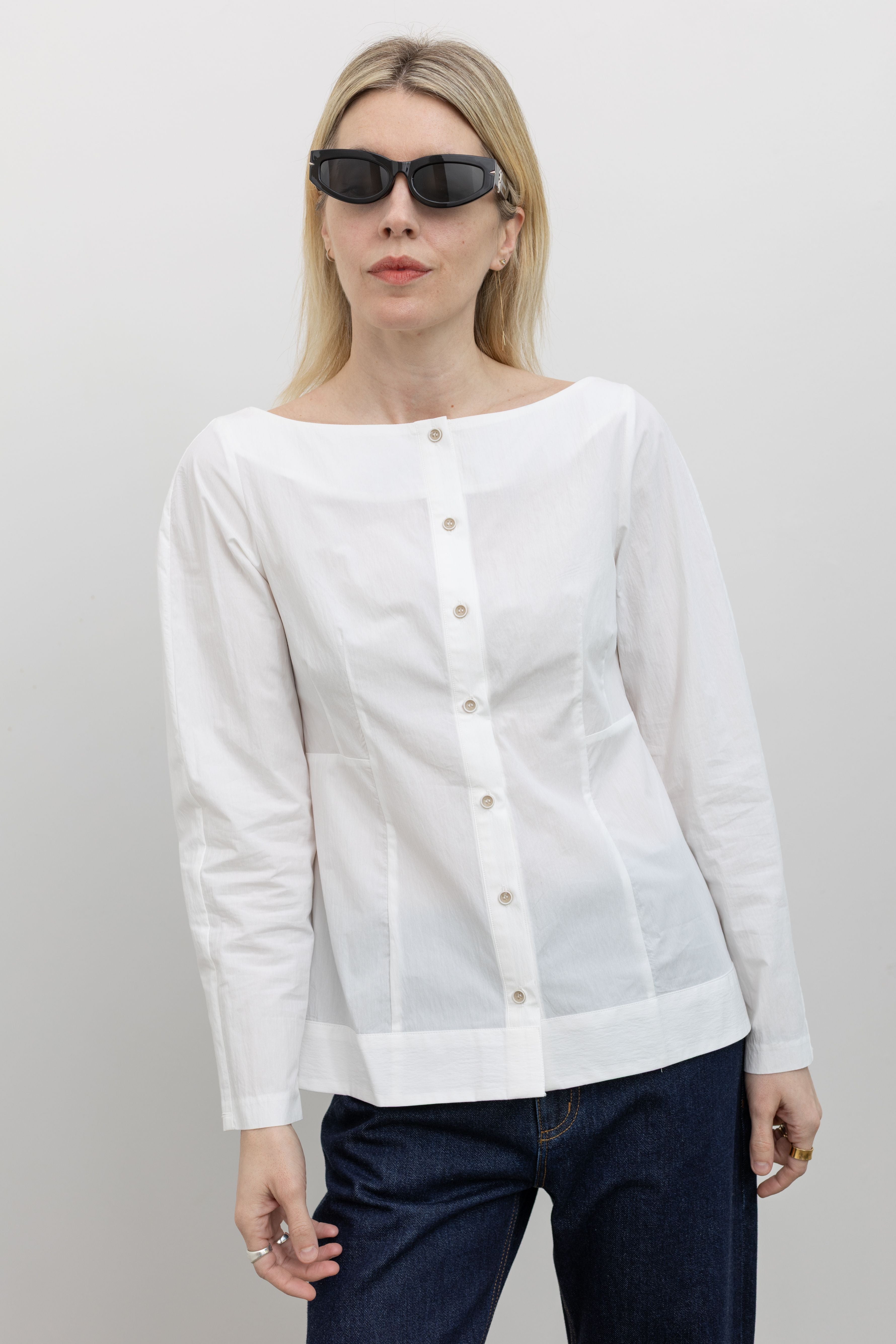 Woman wearing Spring fashion in a Collective White Tailored Boat Neck Button Down Shirt and dark wash jeans with sunglasses at Alas Eius 