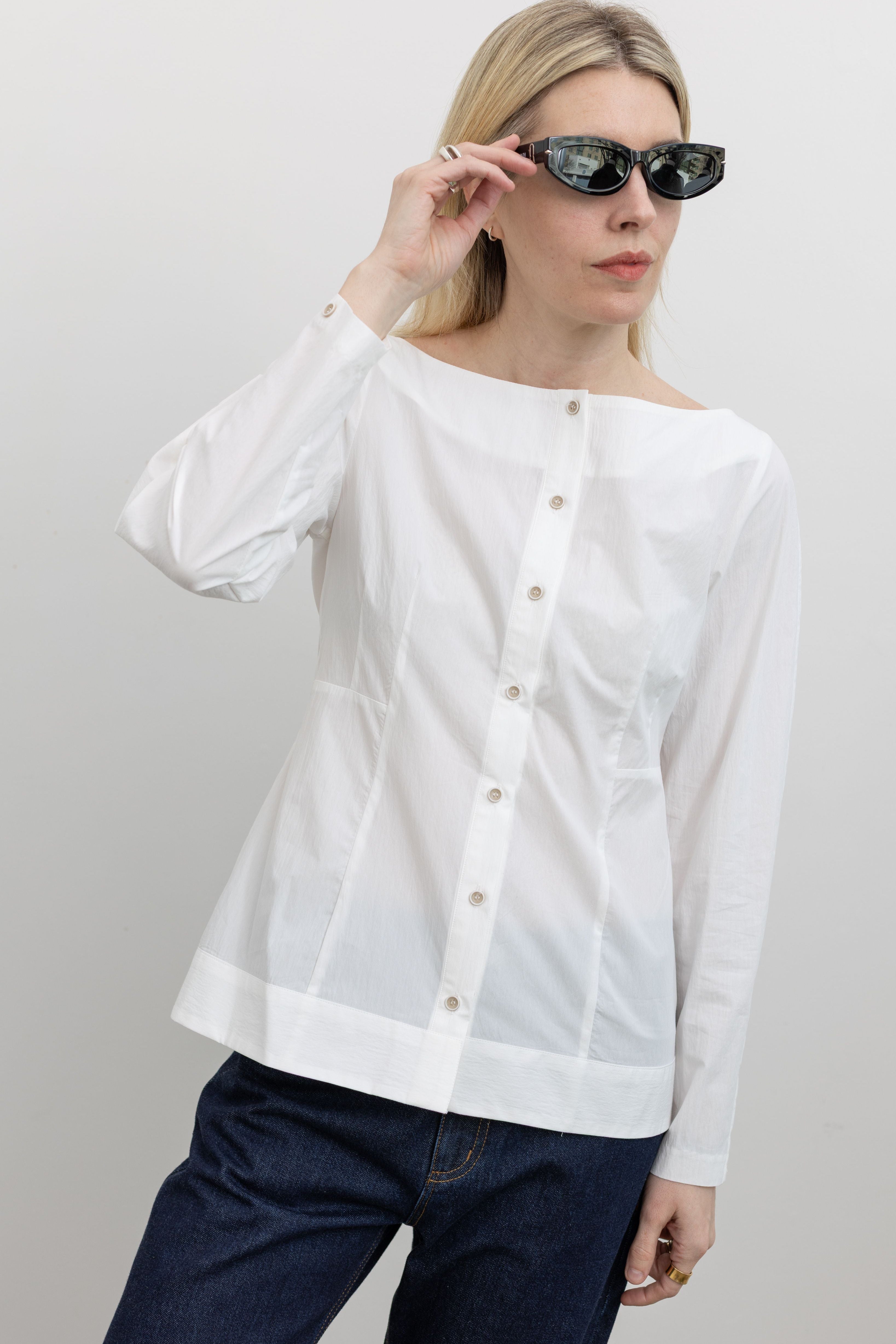 Woman wearing Spring fashion in a Collective White Tailored Boat Neck Button Down Shirt and dark wash jeans with sunglasses at Alas Eius 