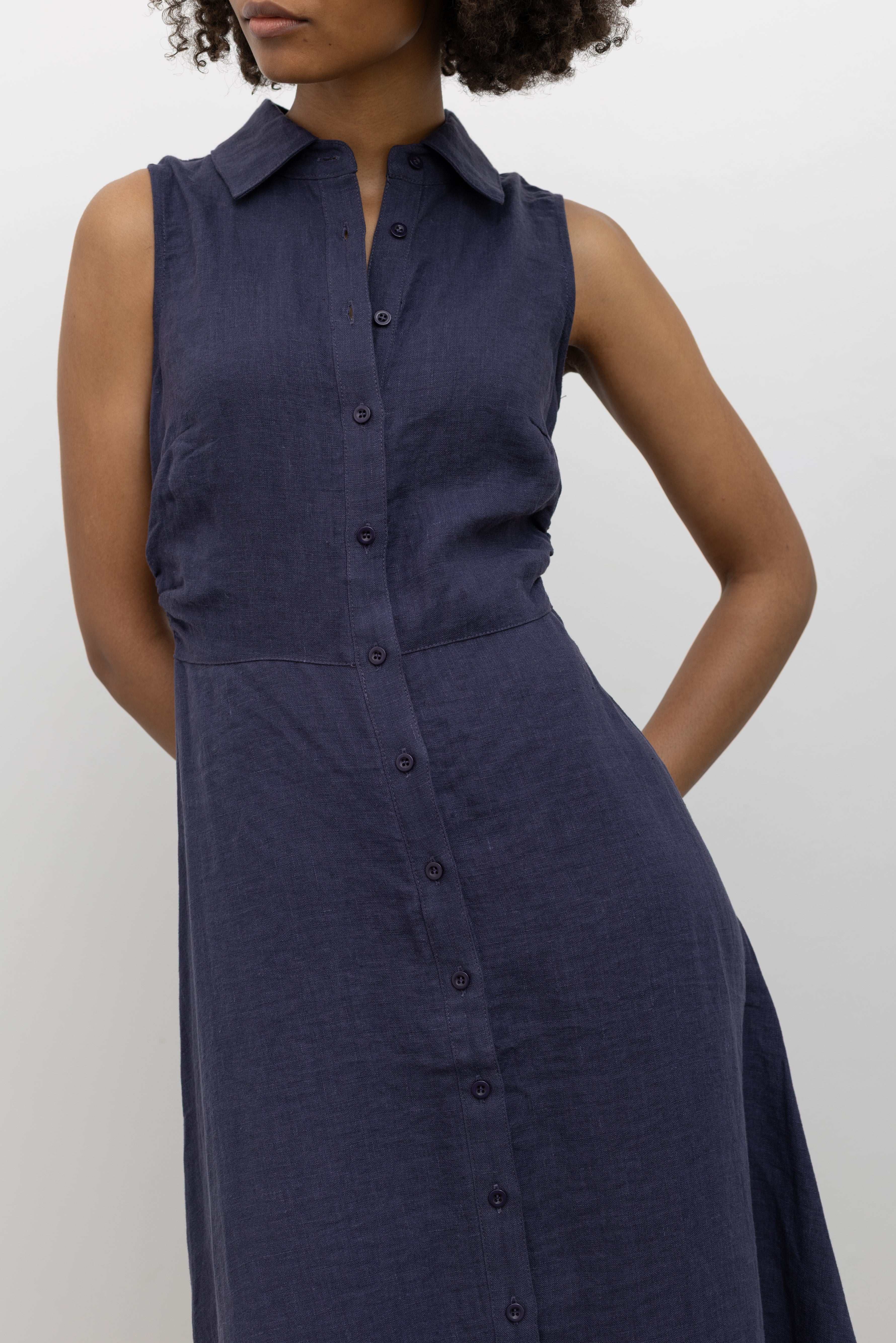 Woman wearing chic summer fashion in a Collective navy blue linen midi length collared shirt dress with buttons down the front at Alas Eius 