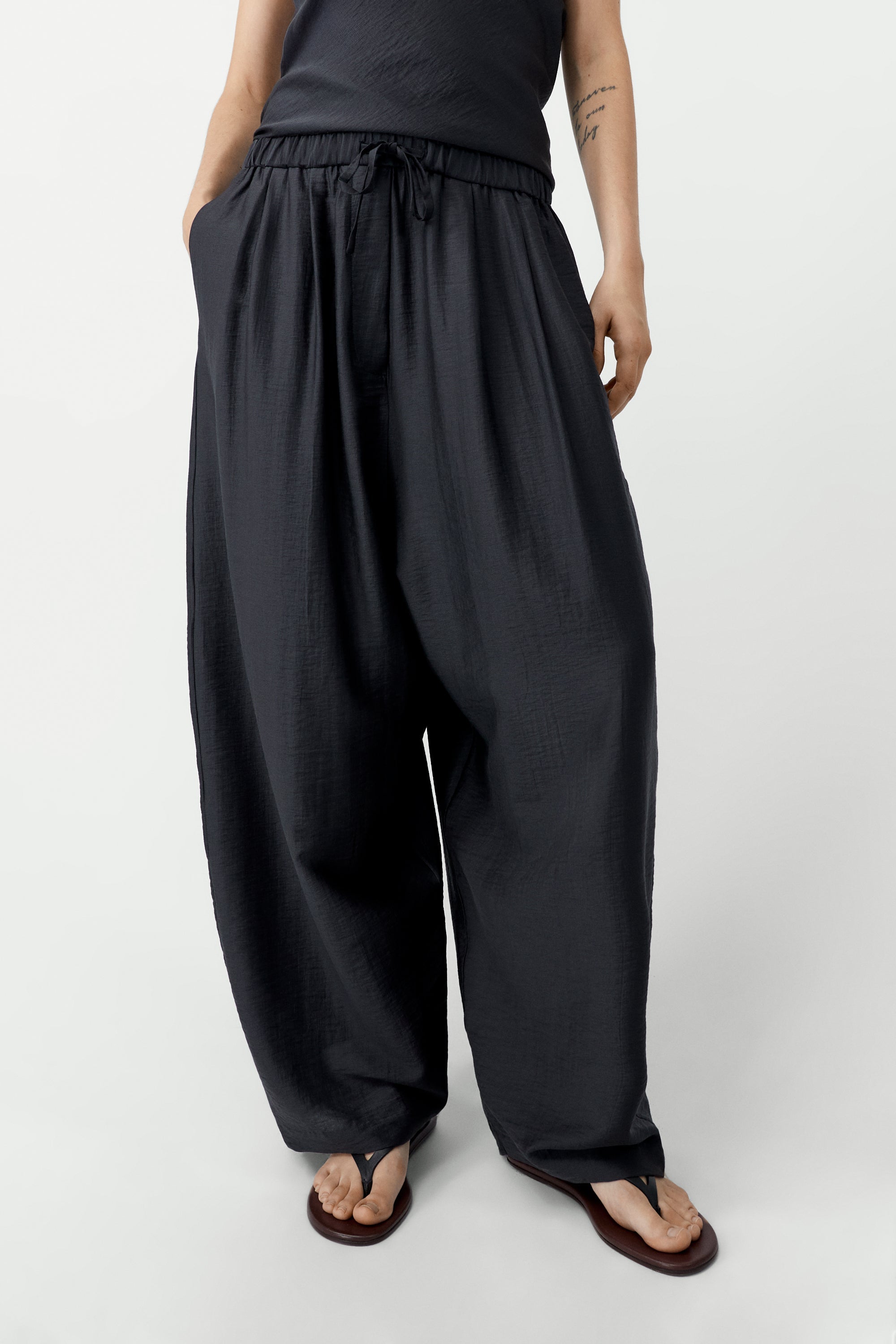 Front view of elevated spring fashion in Cordera espresso brown maxi pants featuring a relaxed fit, drawstring elastic waistband, and side pockets at Alas Eius. 