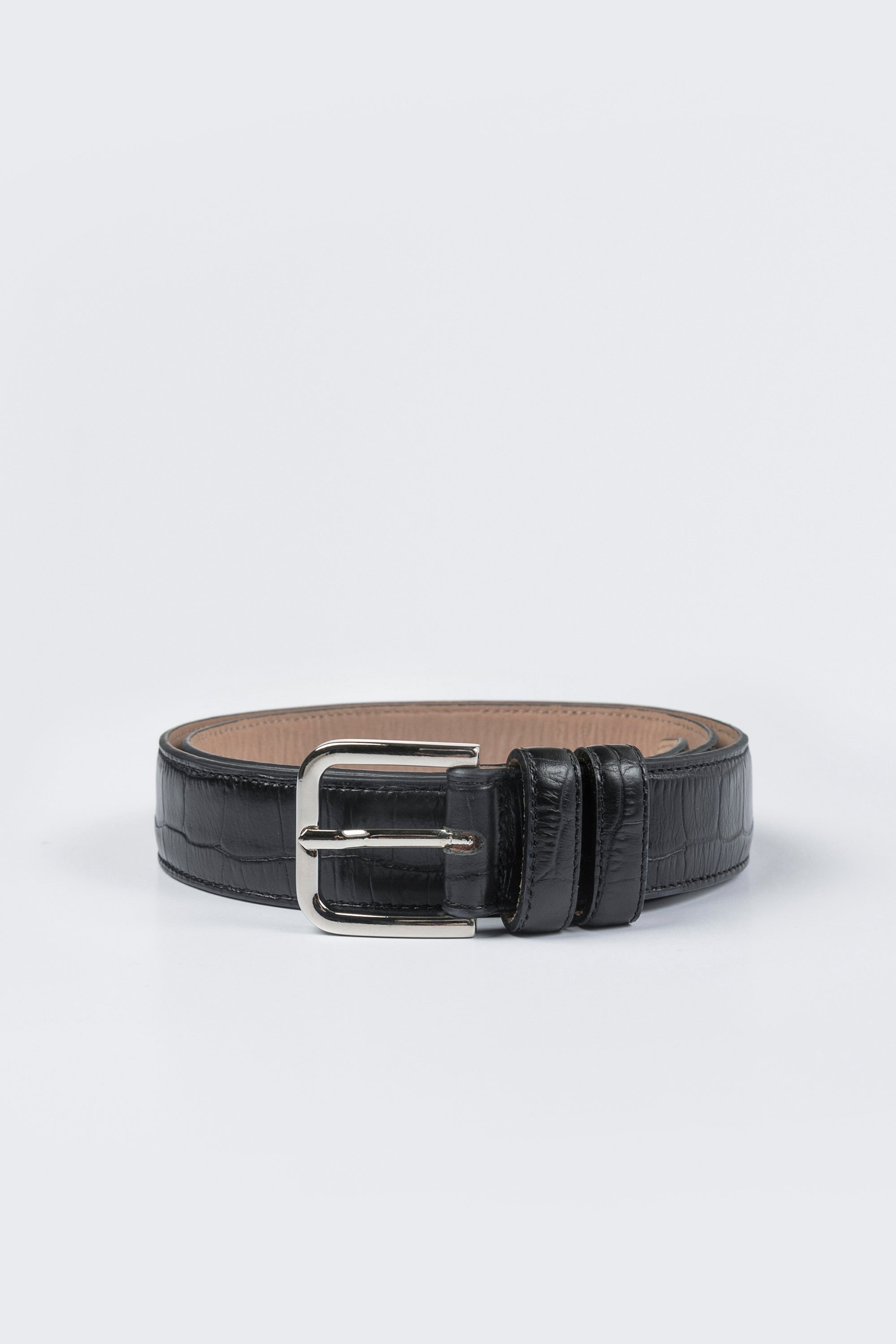 Close-up product view of a classic and chic Cordera black leather crocodile texture pattern belt with a silver buckle at an Alas Eius store. Made in Spain. 