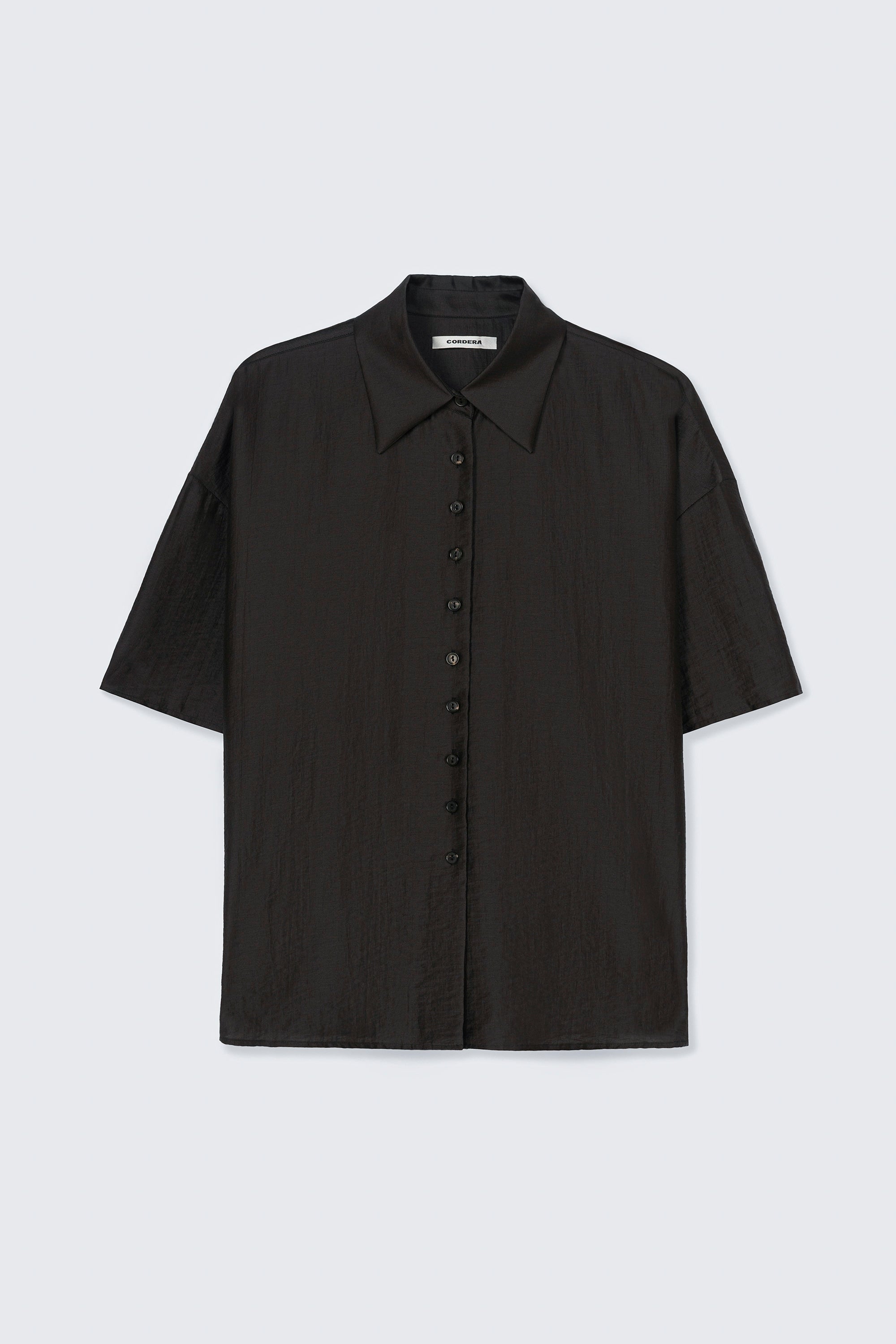Front product view of the Cordera Espresso Brown Short Sleeve Button Front Shirt featuring an oversized, cocoon-shape, roomy short sleeves, pointy collar, small contrasting buttons down the front at an Alas Eius store. Made in Spain. 