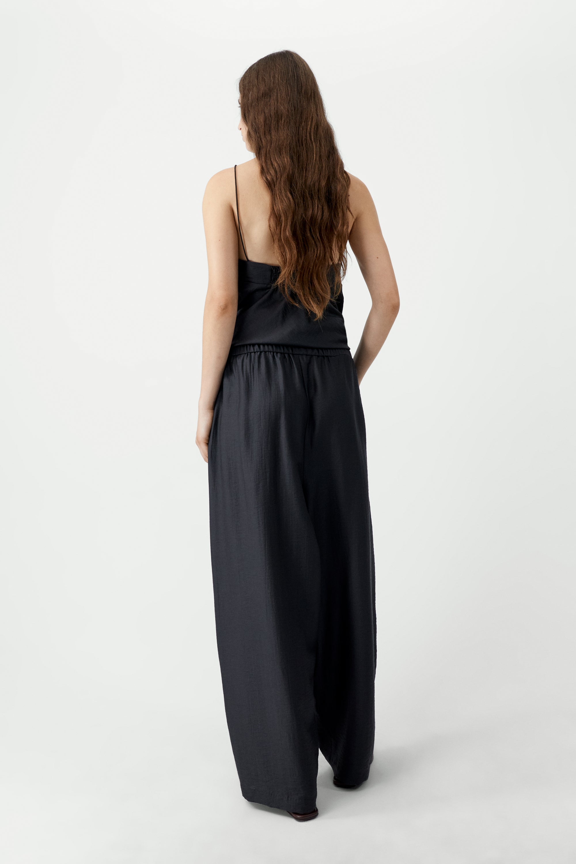 Back view of elevated spring fashion in Cordera espresso brown maxi pants featuring a relaxed fit, drawstring elastic waistband, and side pockets at Alas Eius. 