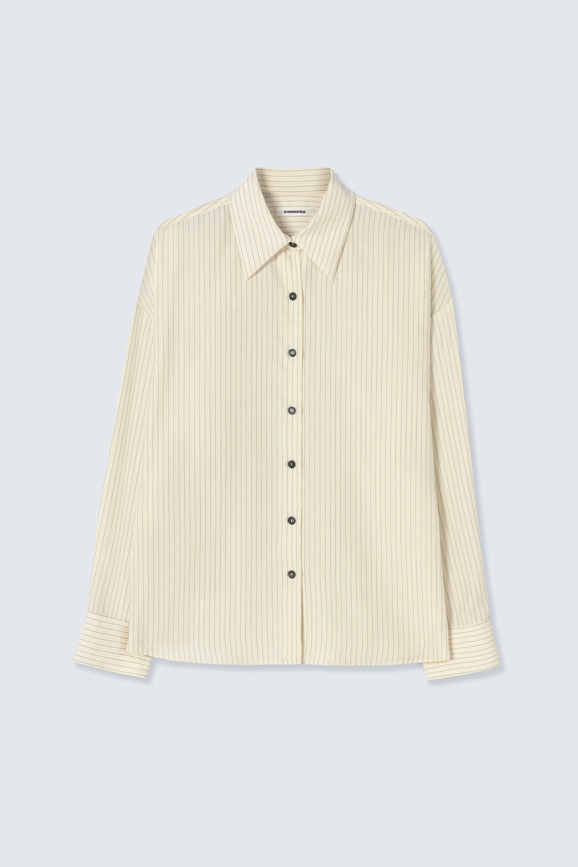 Front view of a classic spring fashion staple in the Cordera Cream Oversized Pencil Striped Shirt featuring an Italian collar and a front button closure at Alas Eius. 