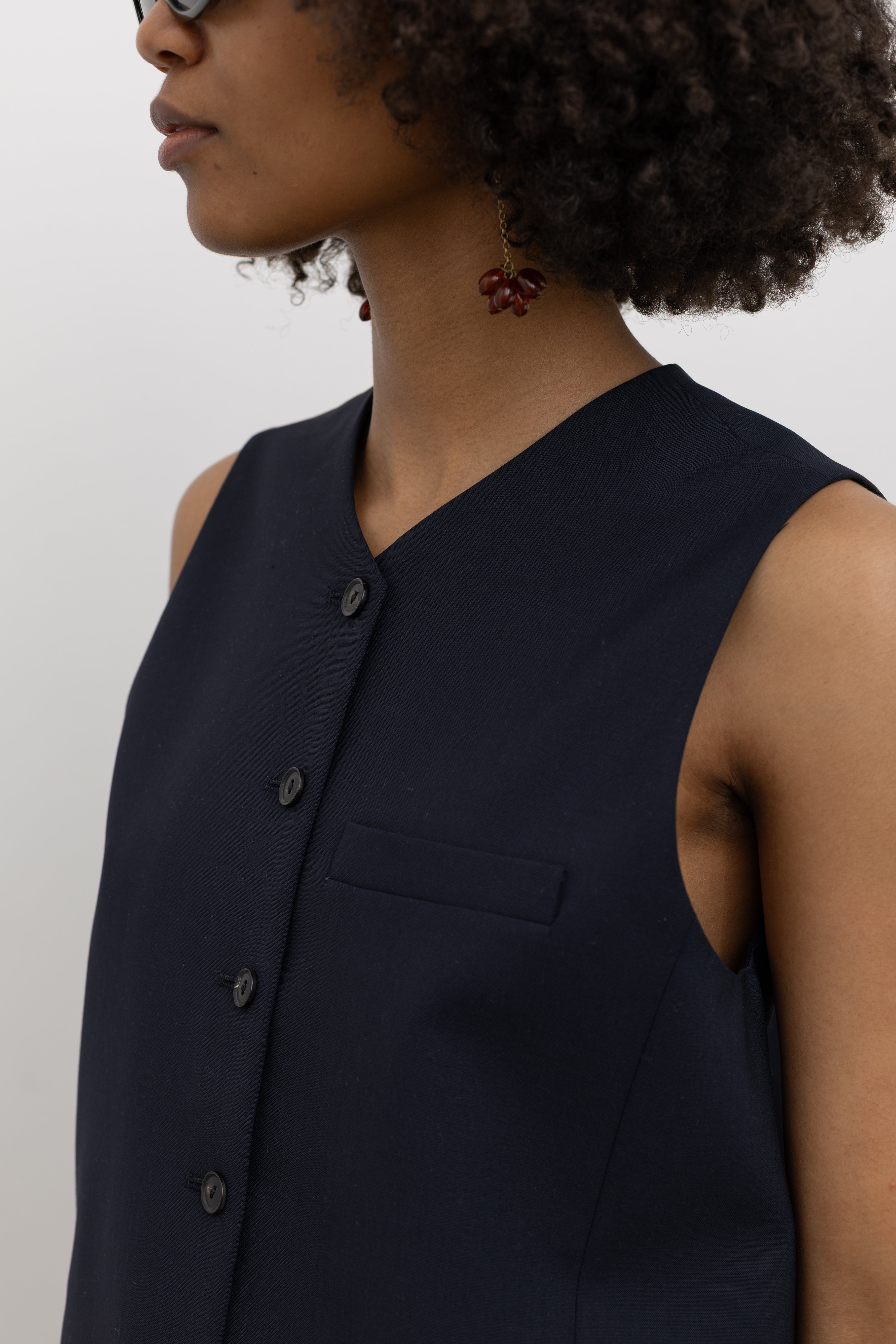Front view of a woman in a Cordera navy tailored vest with V-neck and button closure at Alas Eius 