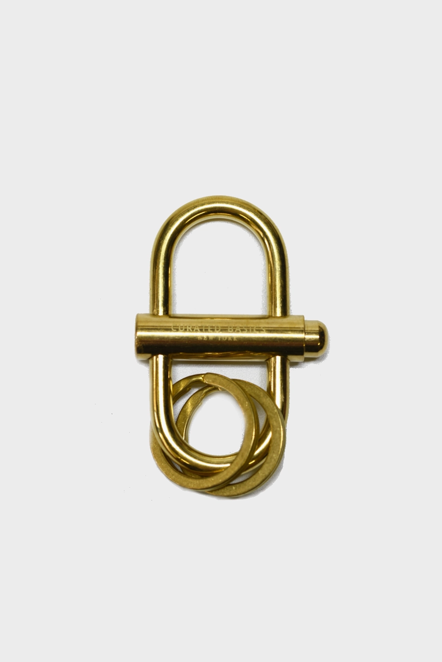 A Curated Basics brand oval brass lock keychain at Alas Eius. 