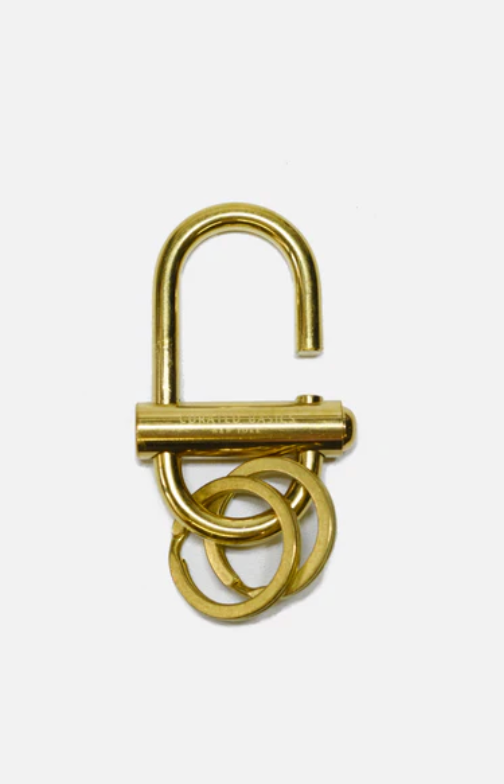A Curated Basics brand oval brass lock keychain at Alas Eius. 