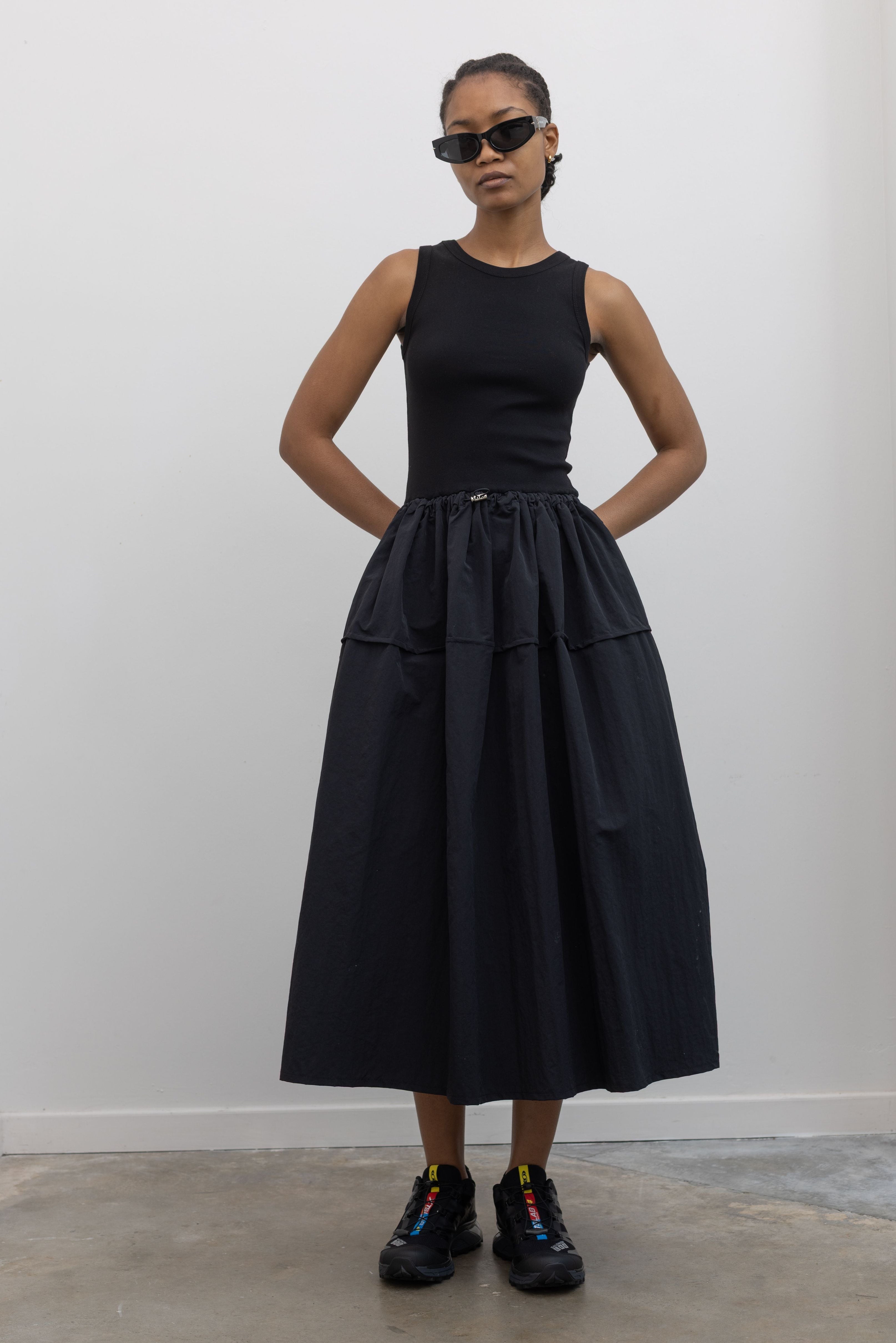 Woman wearing a black sleeveless dress with salomon sneakers