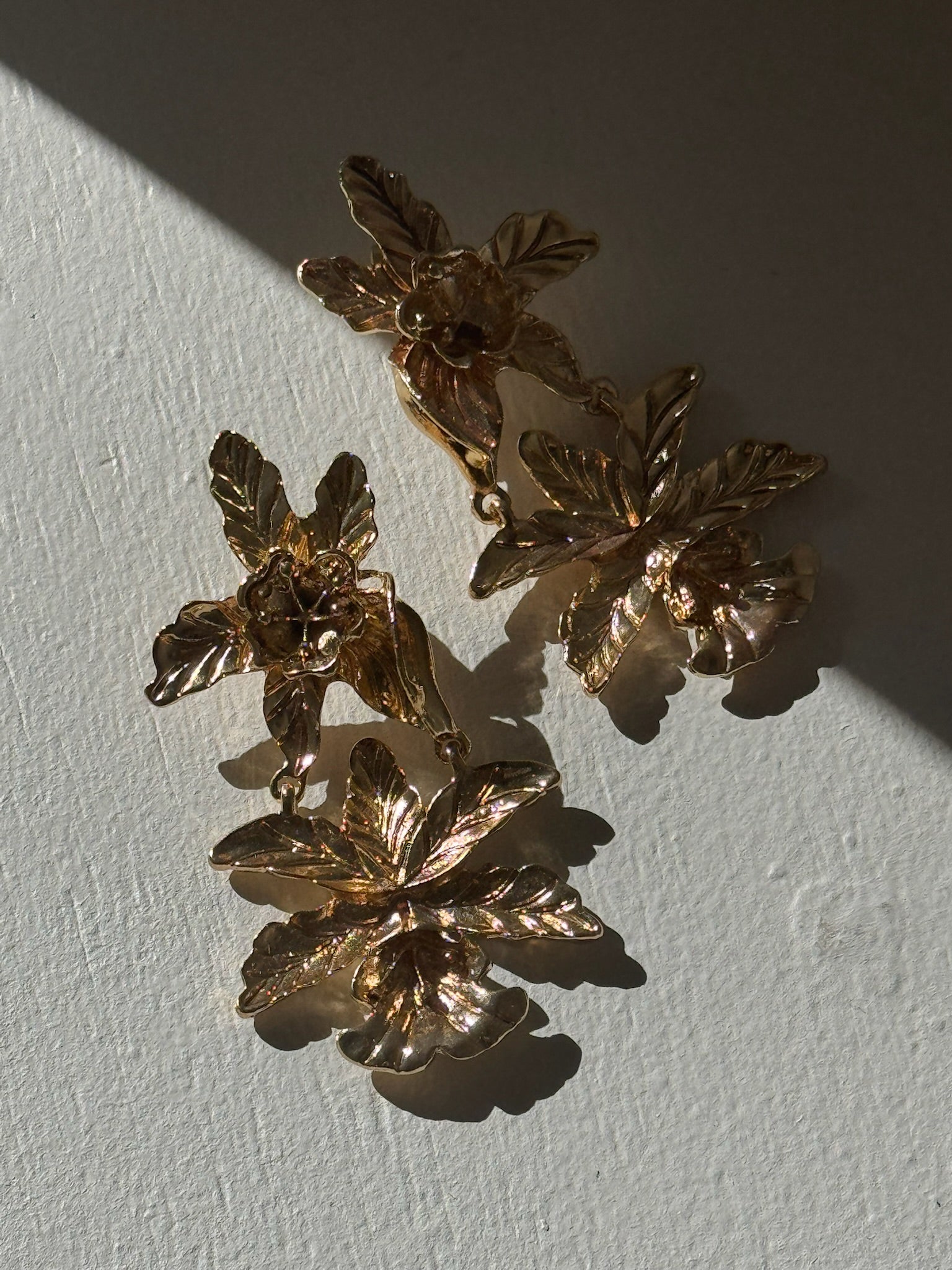 Pair of gold floral earrings on a light gray background