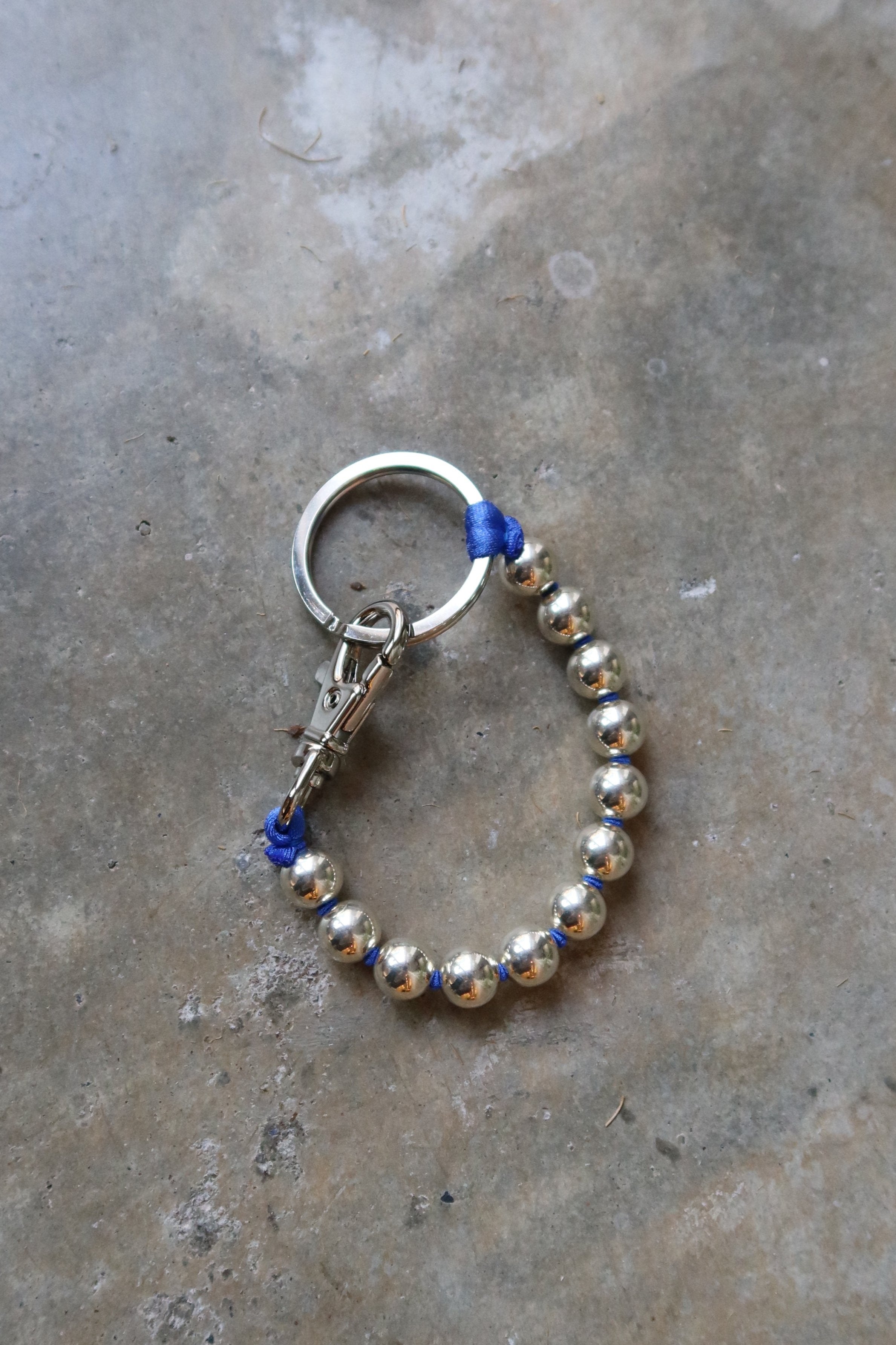 Ina Seifart Sterling Silver And Blue Ribbon Key or Phone Chain with elastic band and threaded 925 silver beads. Made with a cobalt blue ribbon thread and key ring and clasp on either end at Alas Eius
