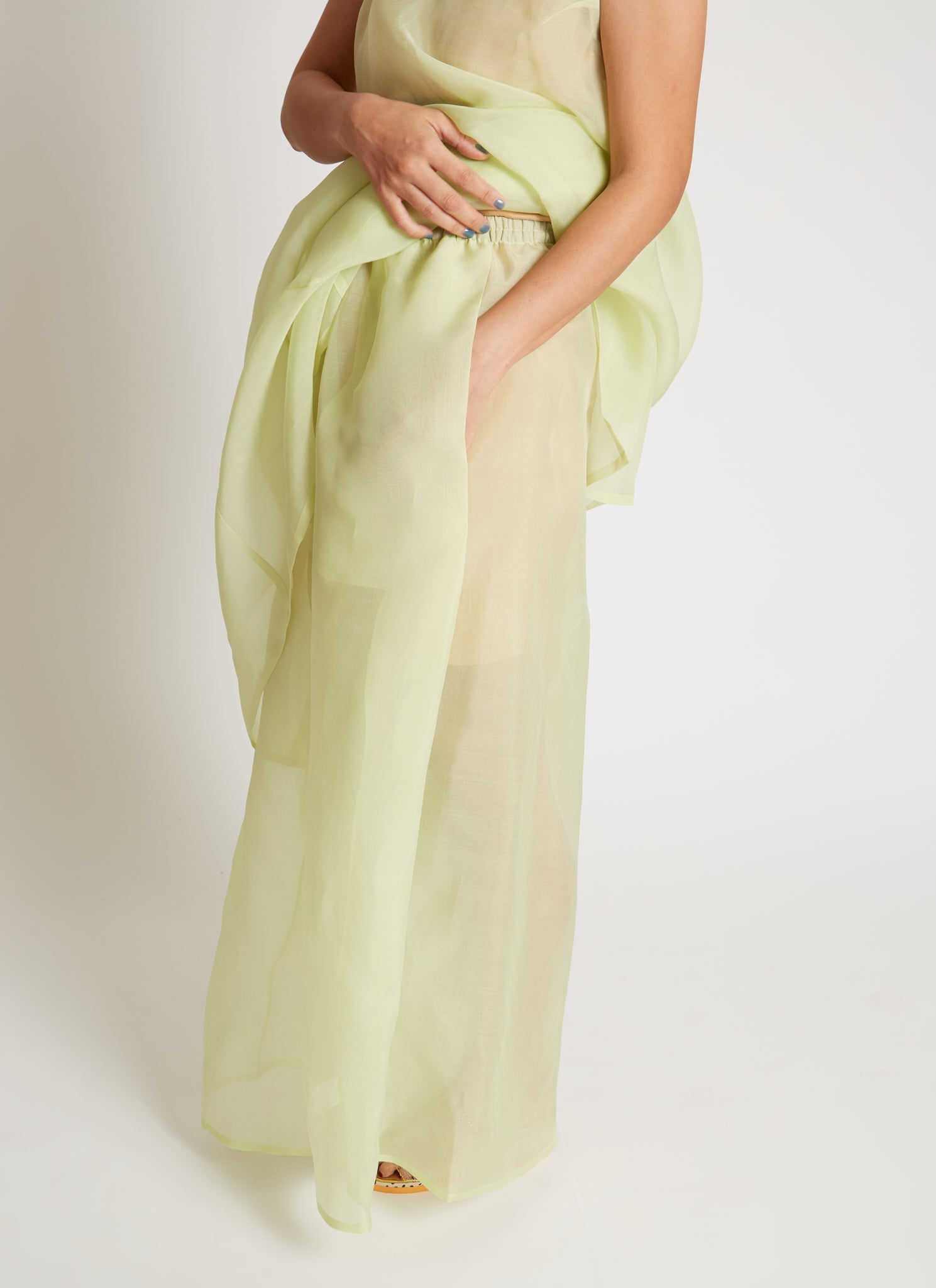 Kaarem SS26 Sheer Green Rice Marble Pleated Silk Organza Pant featuring a wide-leg silhouette, deep side pleats, and finished by a single artisan with a hand-drawn pattern and a delicate blind-hem stitch, featuring an elastic waistband and side pockets for practical ease at Alas EIus.