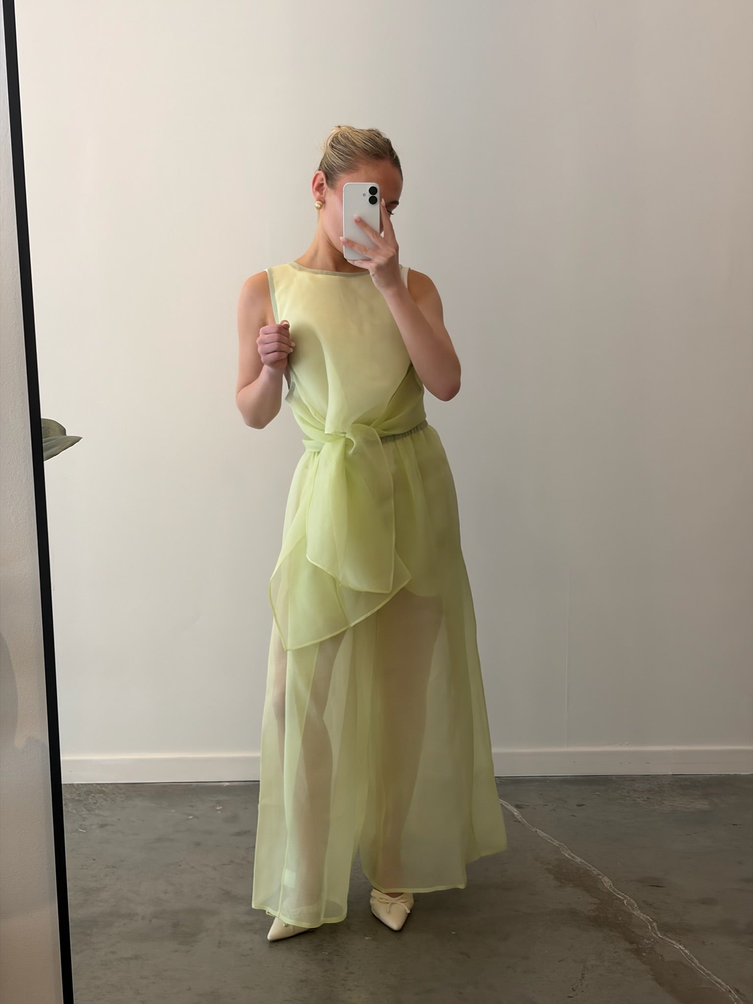 Woman standing wearing elegant spring fashion in Kaarem Green Rice Urchin Sleeveless Silk Organza Tie Top featuring sheer layering and invisible hand-stitched hems for a seamless, ethereal finish at Alas Eius.
