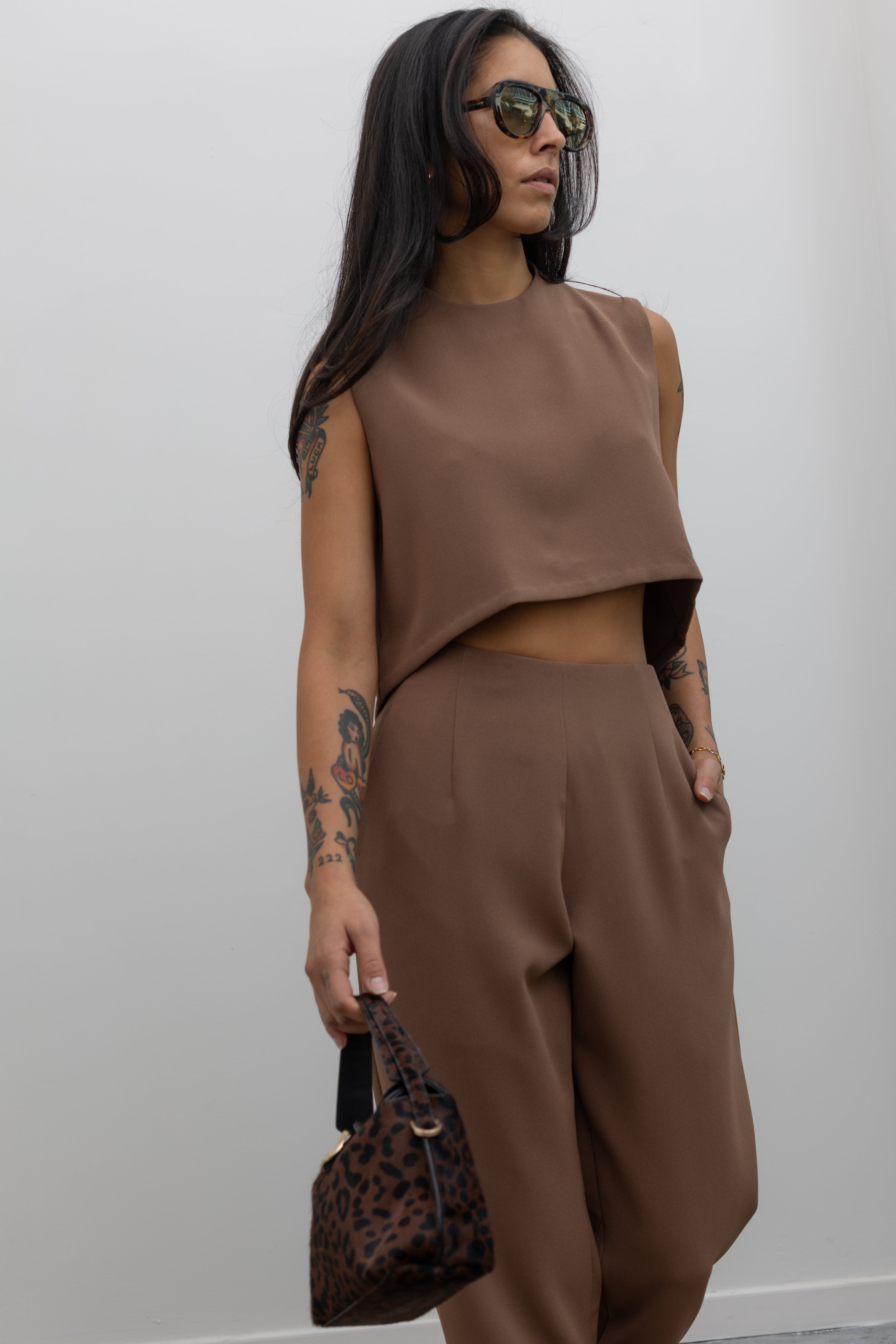 3/4 view of a woman standing wearing spring fashion in the Kaarem Cacao Sua Tapered Trouser Pocket Pant with the coordinating top to make the perfect capsule wardrobe set at Alas Eius.