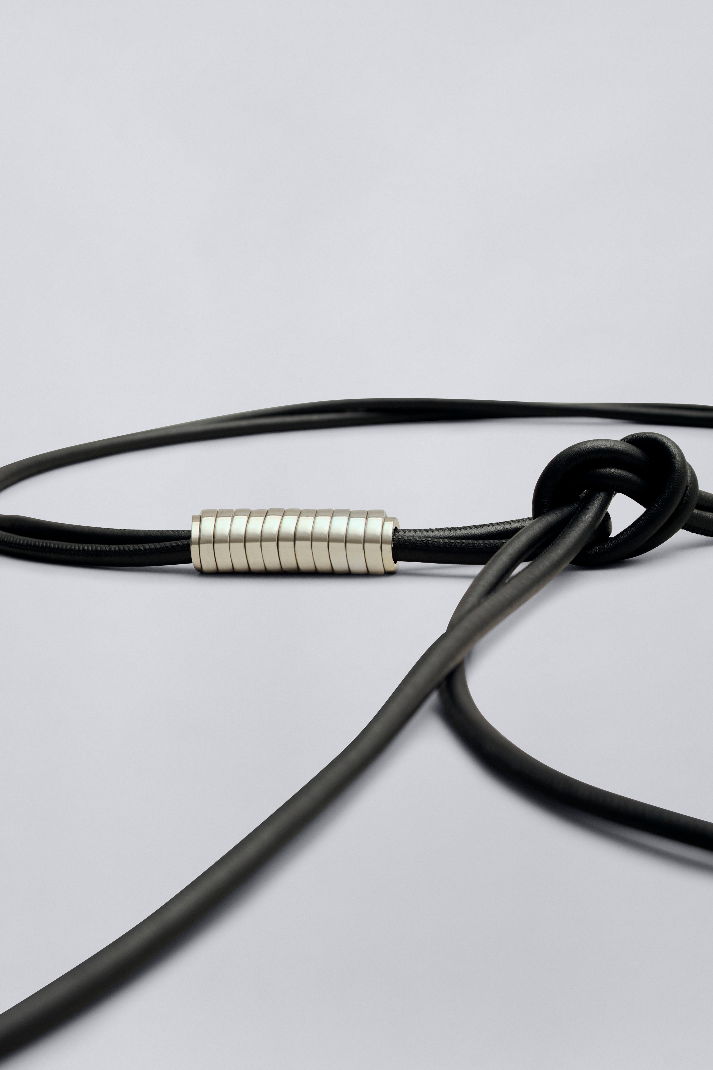 Close-up product view of a contemporary womenswear Kallmeyer Lowell Black Leather Wrap cord belt with silver beaded detail at Alas Eius.