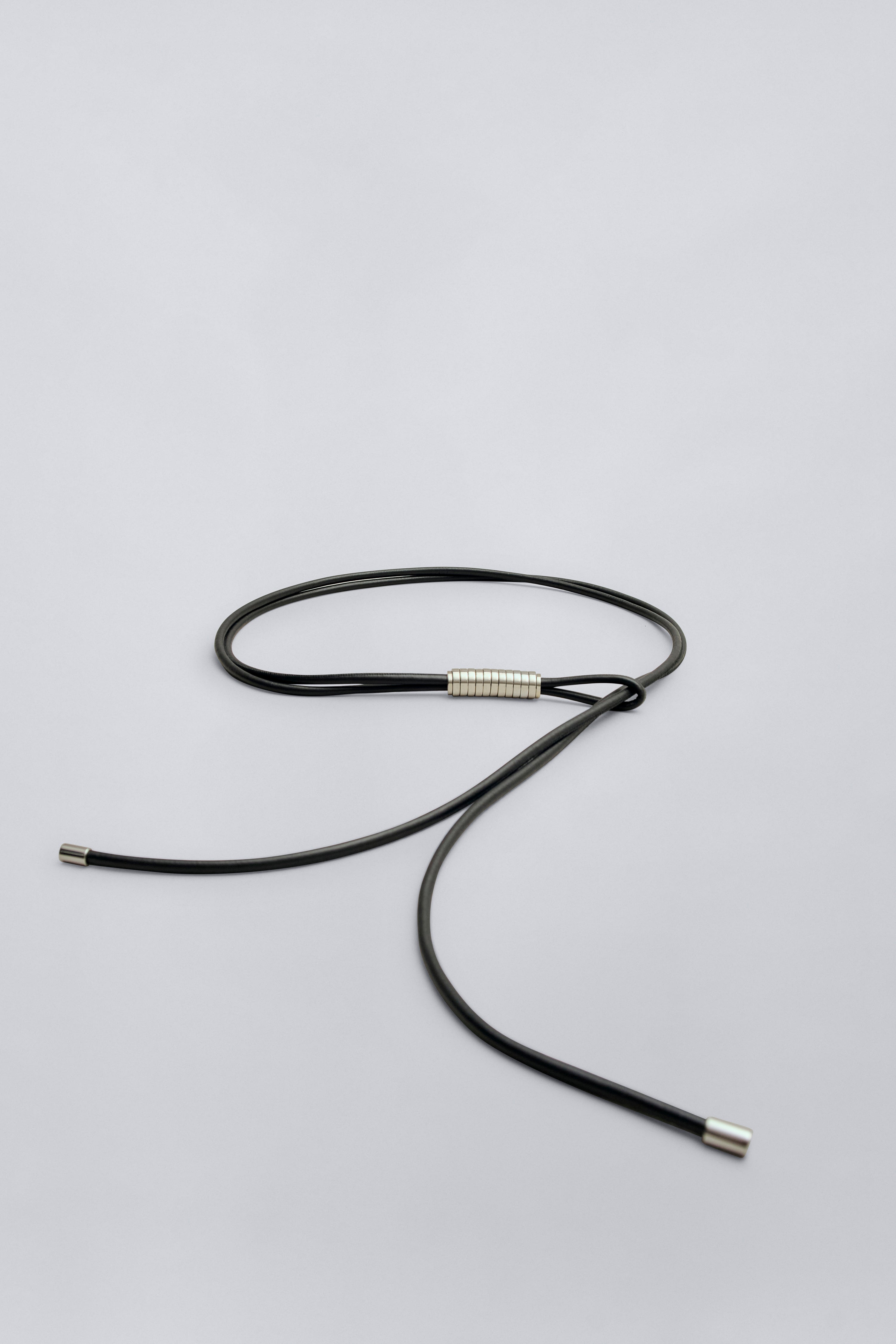 Product view of a chic modern minimalist Kallmeyer black leather cord belt with silver beaded detail at Alas Eius.