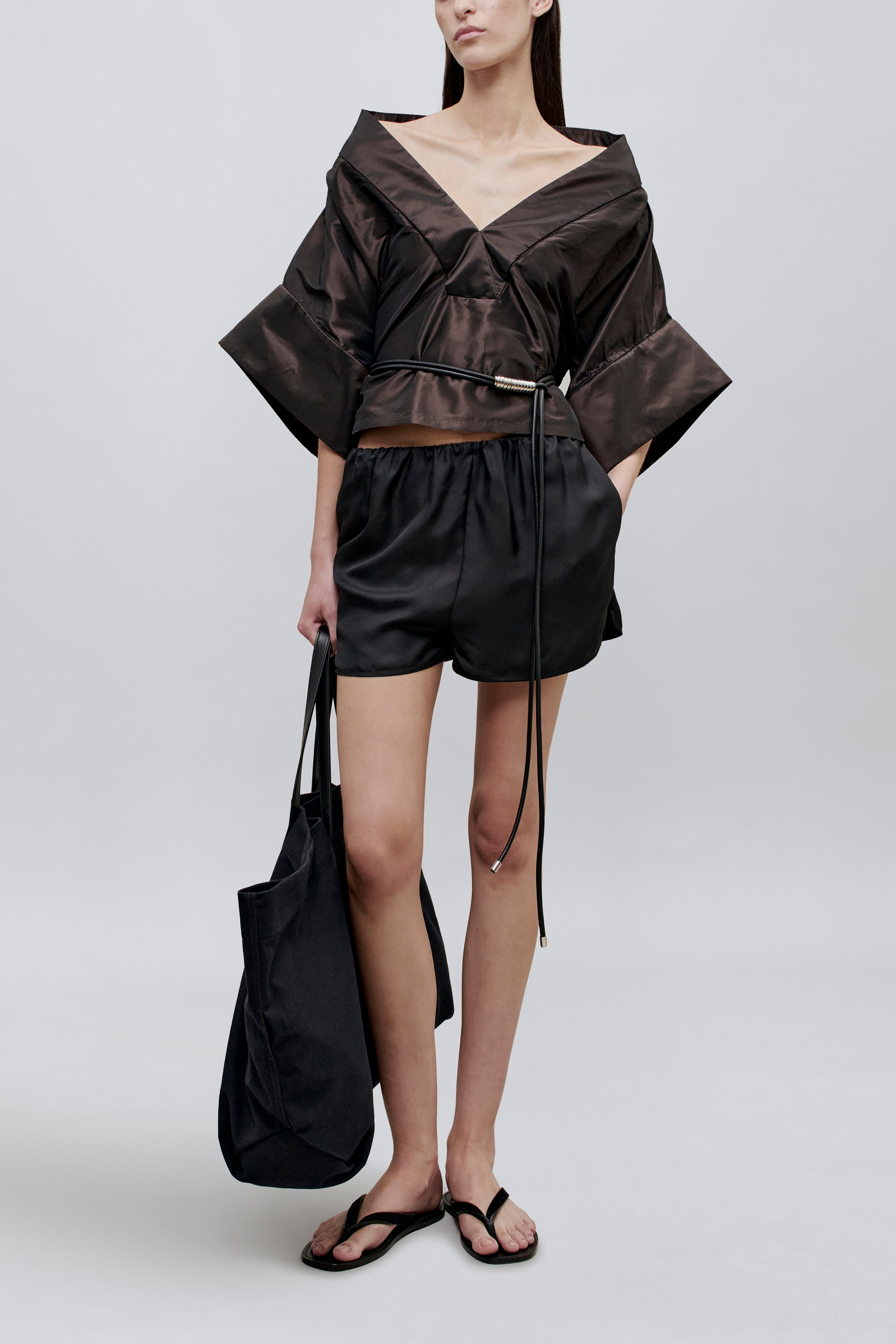 Front view of a woman wearing chic and contemporary fashion in a Kallmeyer Espresso Silk Taffeta Winslow Top featuring a crisp silk taffeta with dramatic structured v-neckline and oversized cuffed tunic sleeves at Alas Eius. Made in New York.