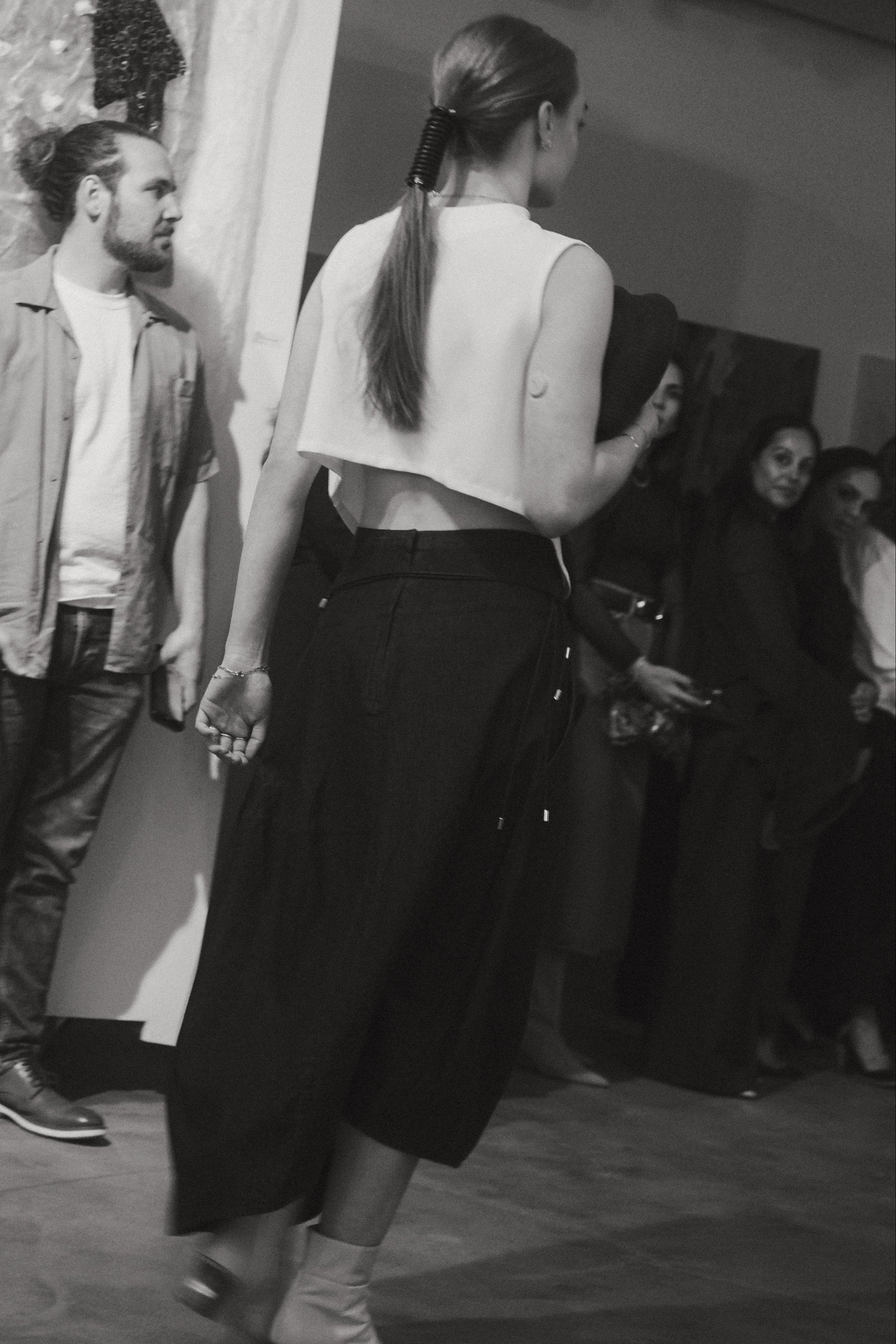 Back view of a woman wearing capsule wardrobe essential style in a Kaarem White Raised Collar Wind Chime Cropped Top at Alas Eius.