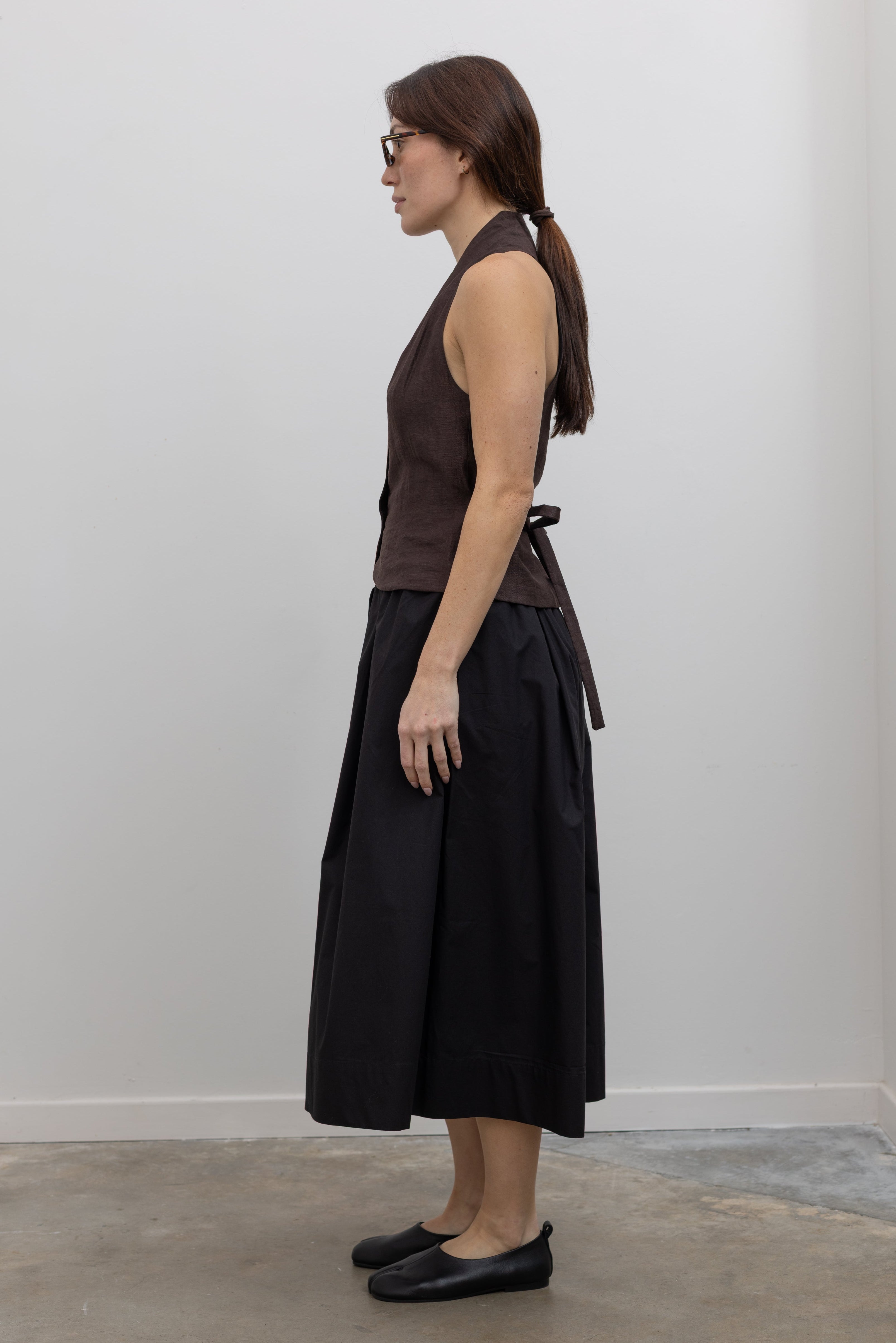 Side view of Woman wearing Spring fashion in a brown linen buttoned vest with flattering Kowtow Black Organic Cotton Elastic Waistband Culottes at Alas Eius