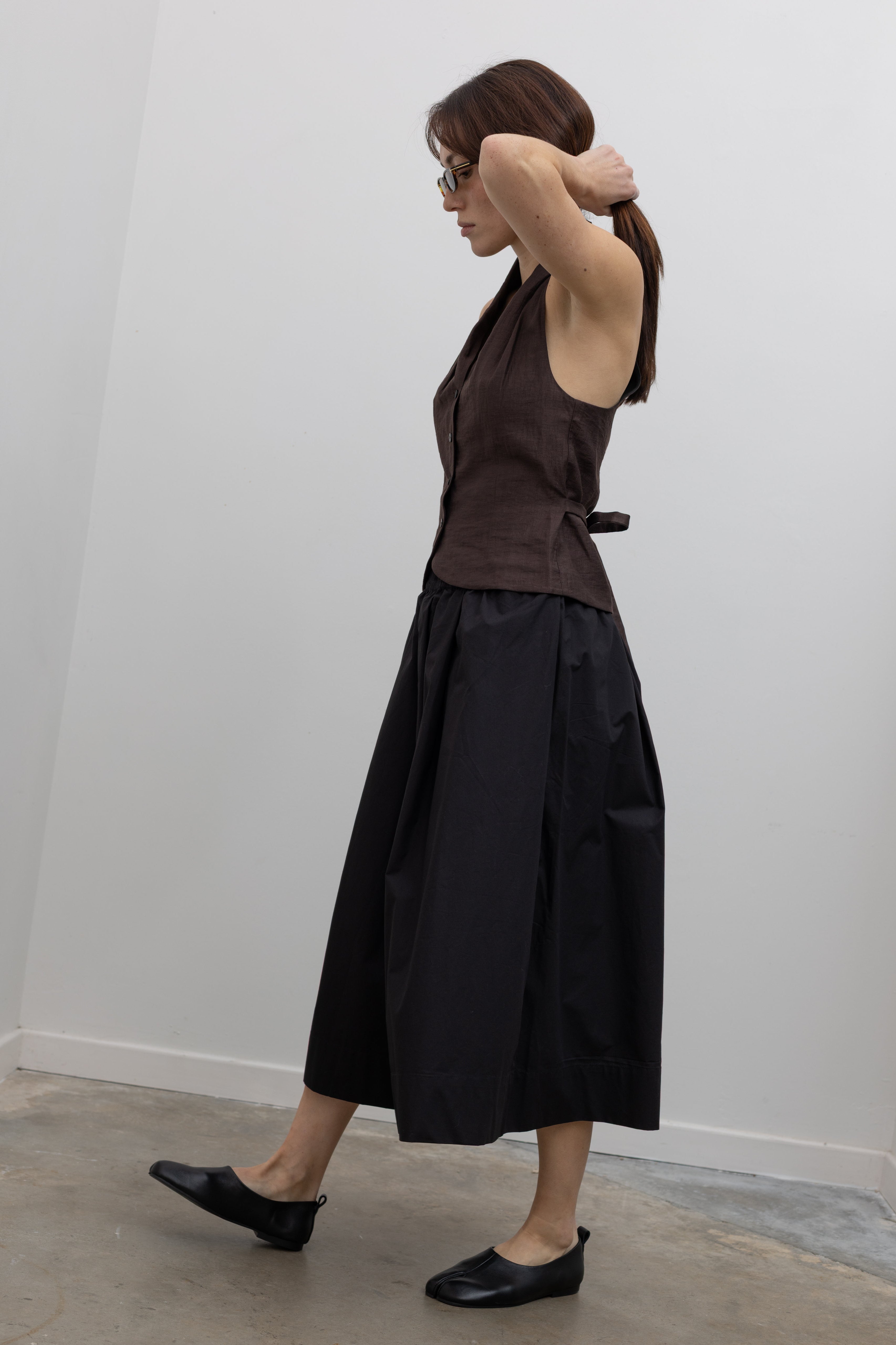 Woman wearing Spring fashion in a brown linen buttoned vest with flattering voluminous Kowtow Black Organic Cotton Elastic Waistband Culottes at Alas Eius