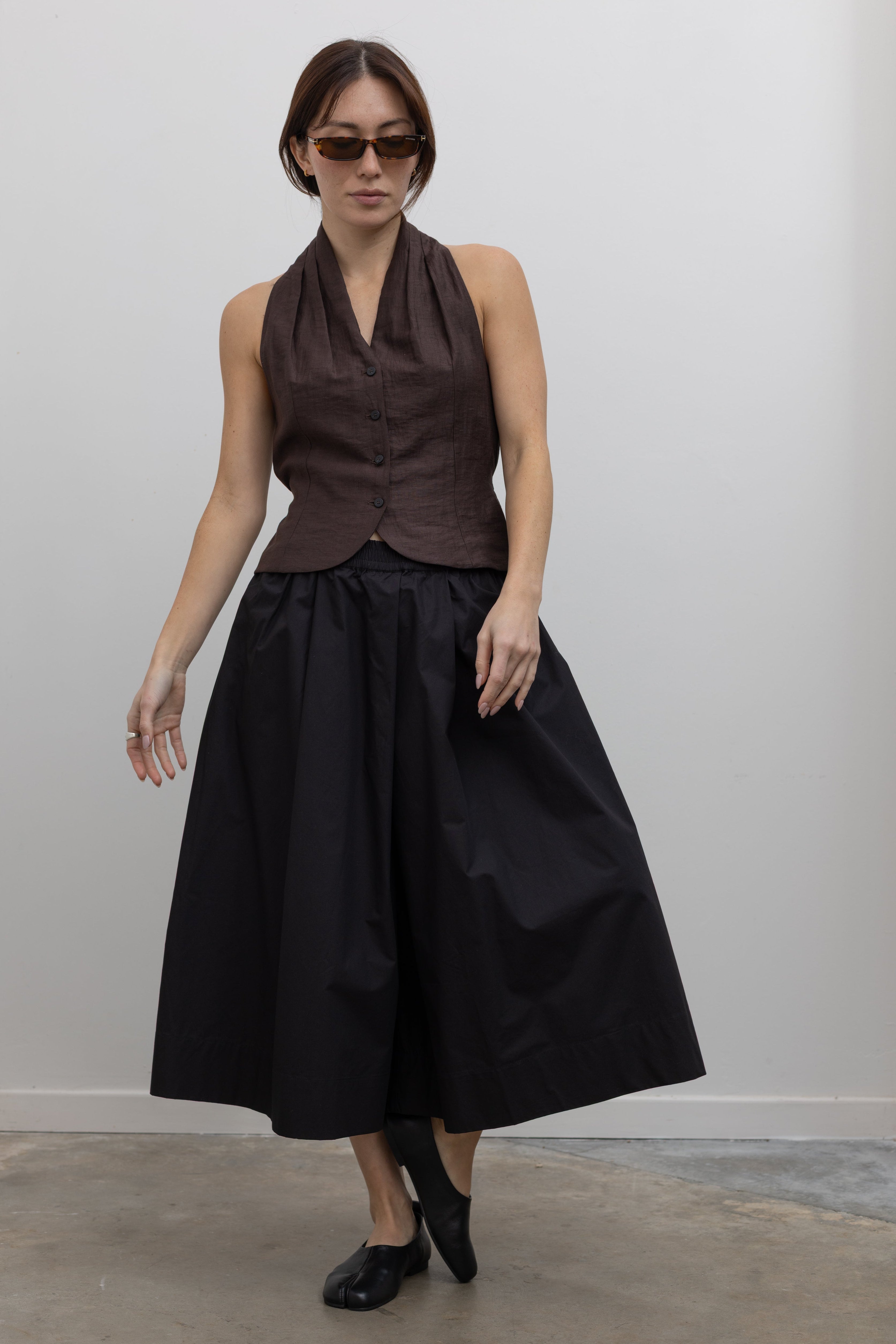 Woman wearing Spring fashion in a brown linen buttoned vest with flattering Kowtow Black Organic Cotton Elastic Waistband Culottes at Alas Eius