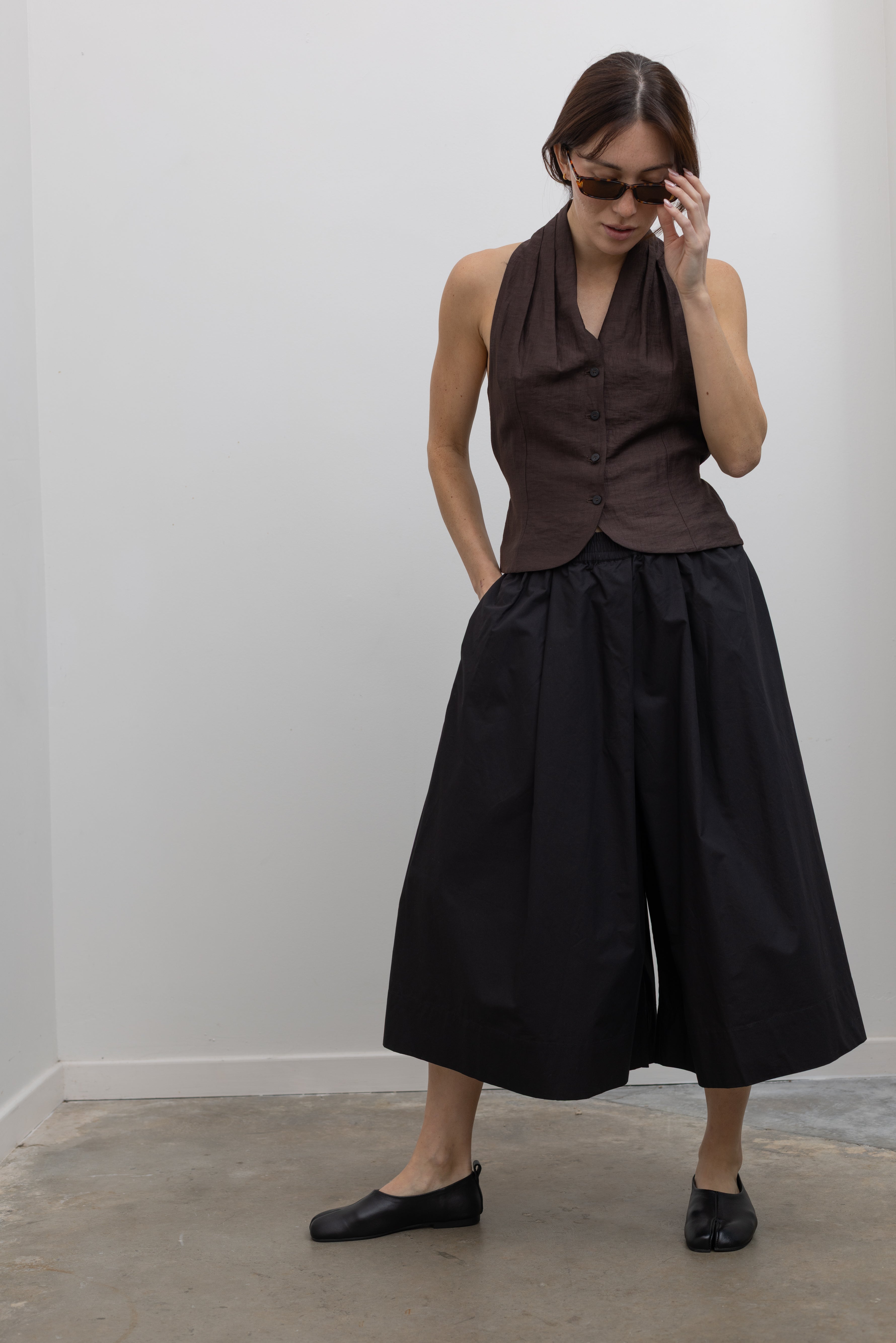 Woman wearing Spring fashion in a brown linen buttoned vest with flattering voluminous Kowtow Black Organic Cotton Elastic Waistband Culottes at Alas Eius