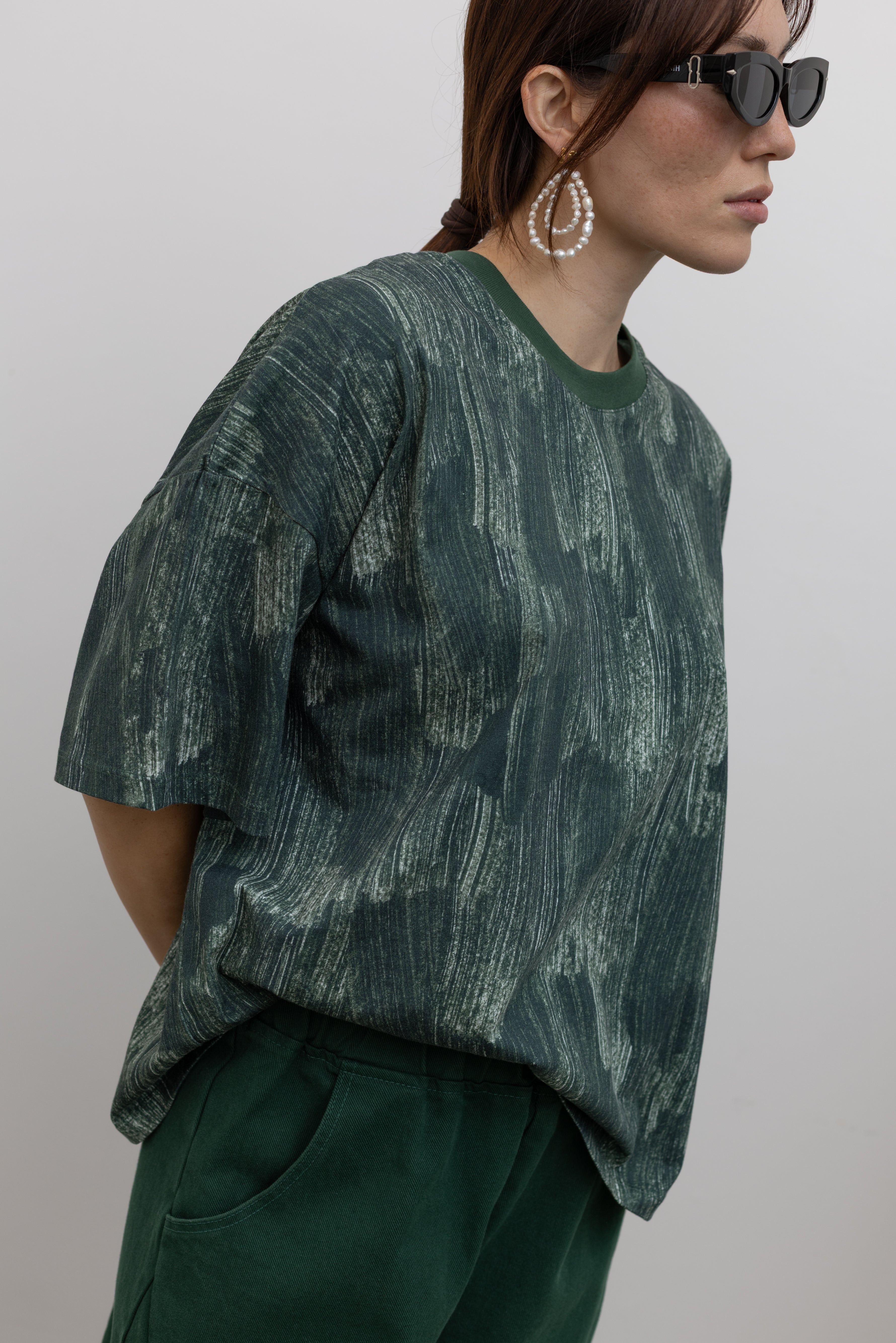 Close-up side view of a Kowtow green oversized short sleeve t-shirt with an all over white brushstroke print at Alas Eius.