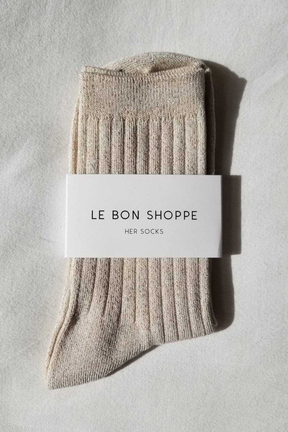 A pair of women's Le Bon Shoppe Spring fashion ribbed crew socks in ivory gold color with sparkles throughout at Alas Eius