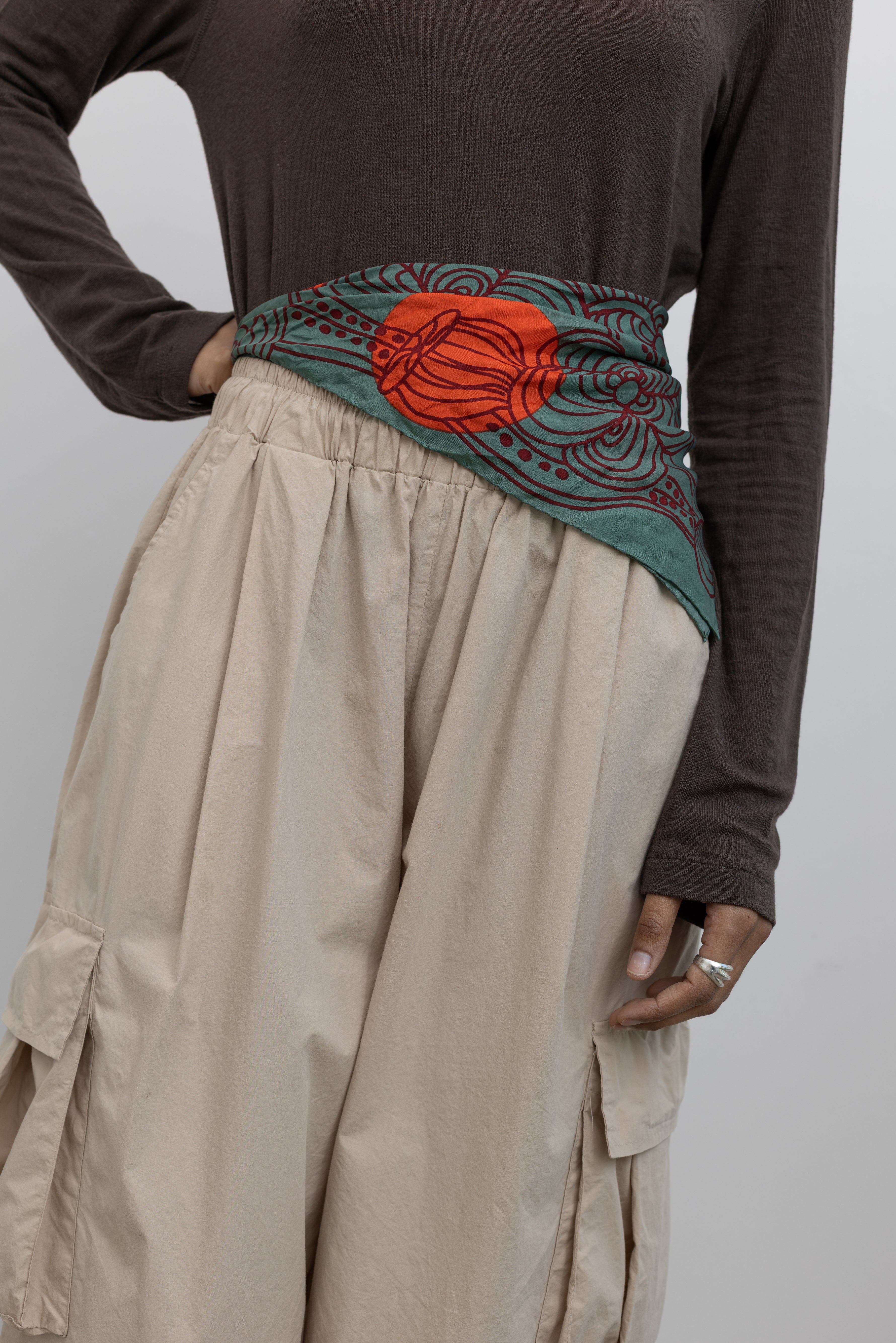 Woman wearing a Les Belles Vagabondes brand mini Khaki Green with Orange and Maroon Floral print Silk Scarf at Alas Eius. 