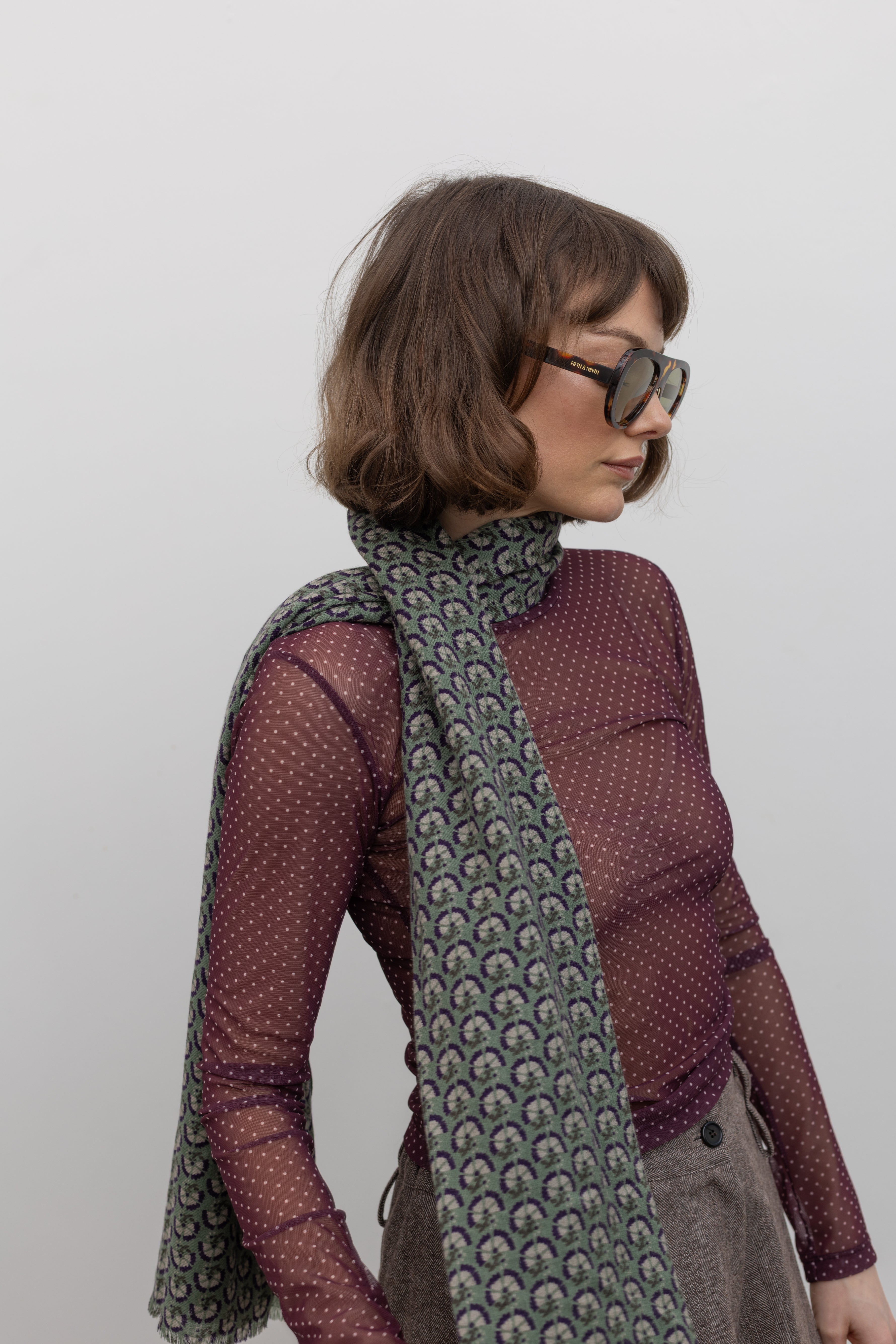 Woman wearing a hand-drawn Les Belles Vagabondes brand Marigold green wool floral print scarf at Alas Eius.