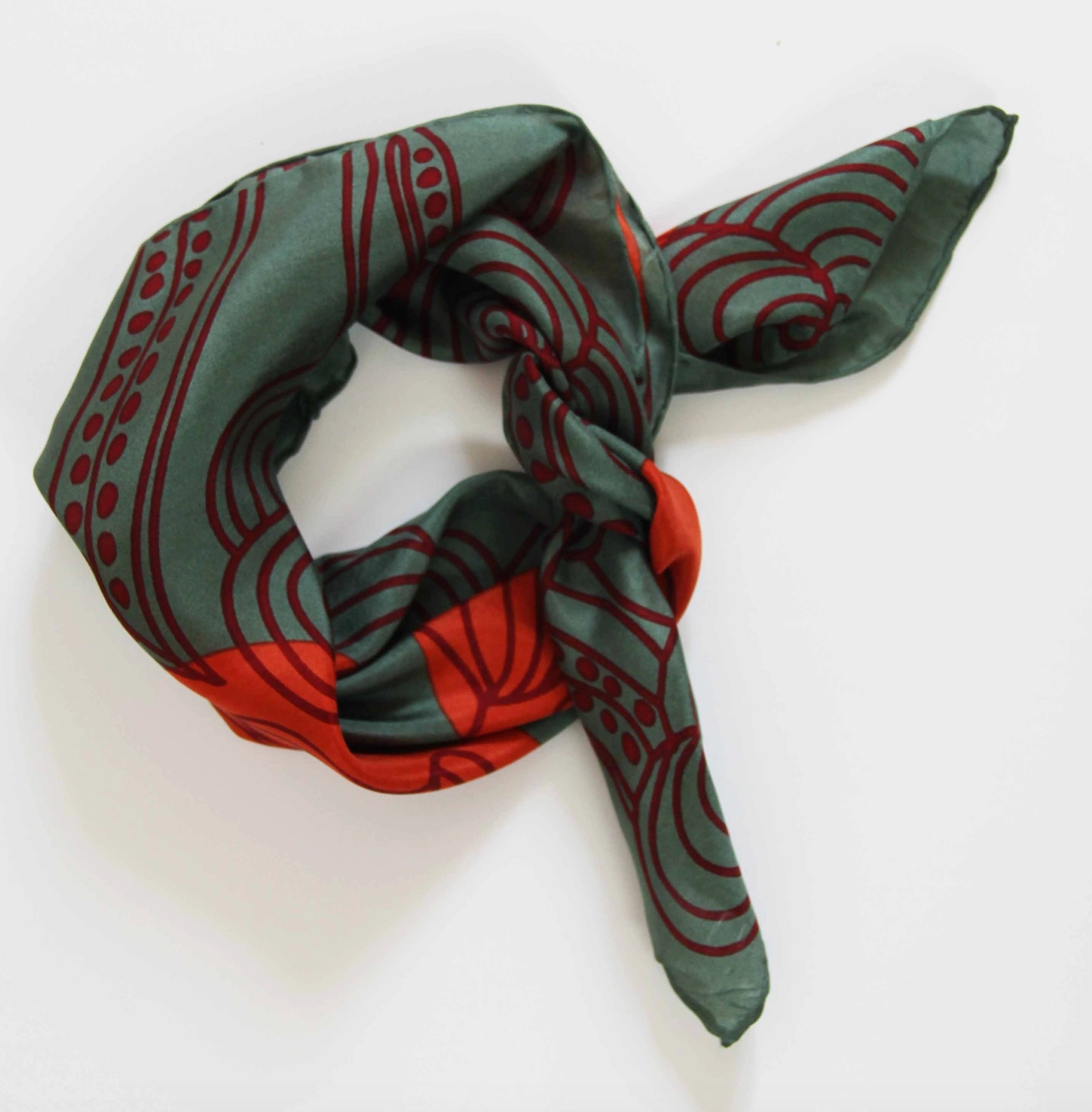 Close-up product view of rolled and tied Les Belles Vagabondes brand mini Khaki Green with Orange and Maroon Floral print Silk Scarf at Alas Eius.