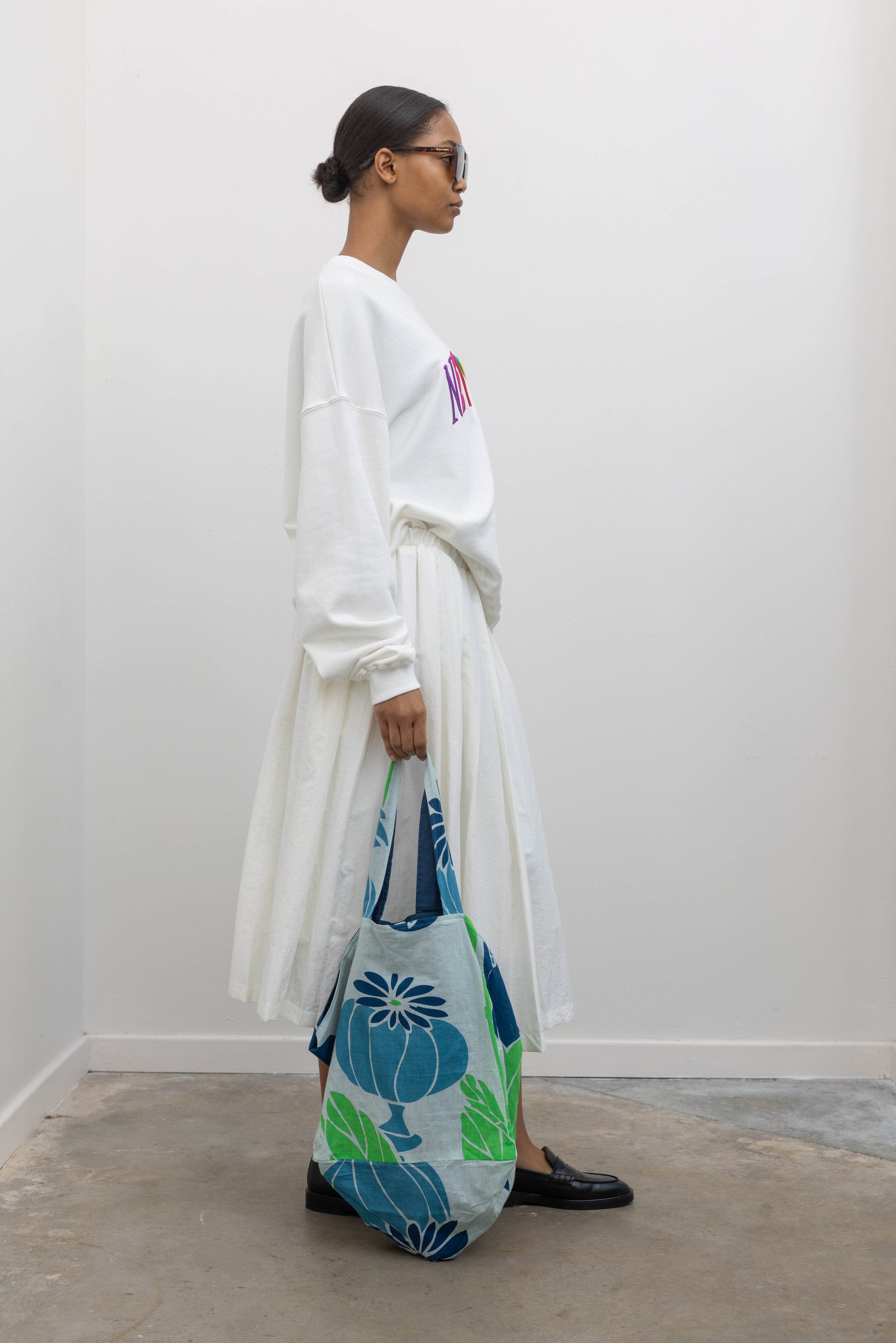 Woman wearing colorful Les Belles Vagabondes brand upcycled organic cotton tote bag with all over vibrant blue and green floral print at Alas Eius. 