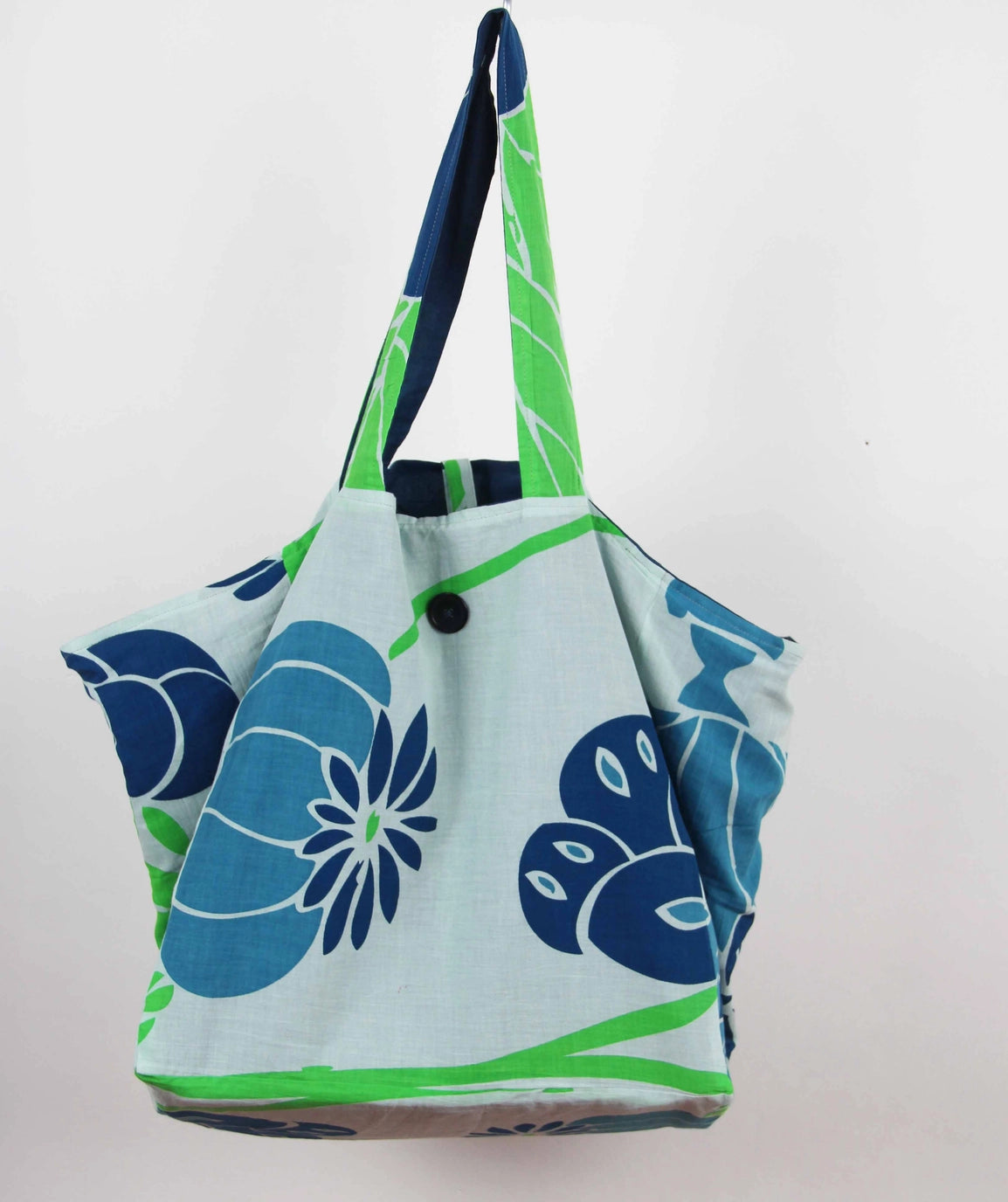 Front product view of a colorful Les Belles Vagabondes brand upcycled organic cotton tote bag with all over vibrant blue and green floral print at Alas Eius. 