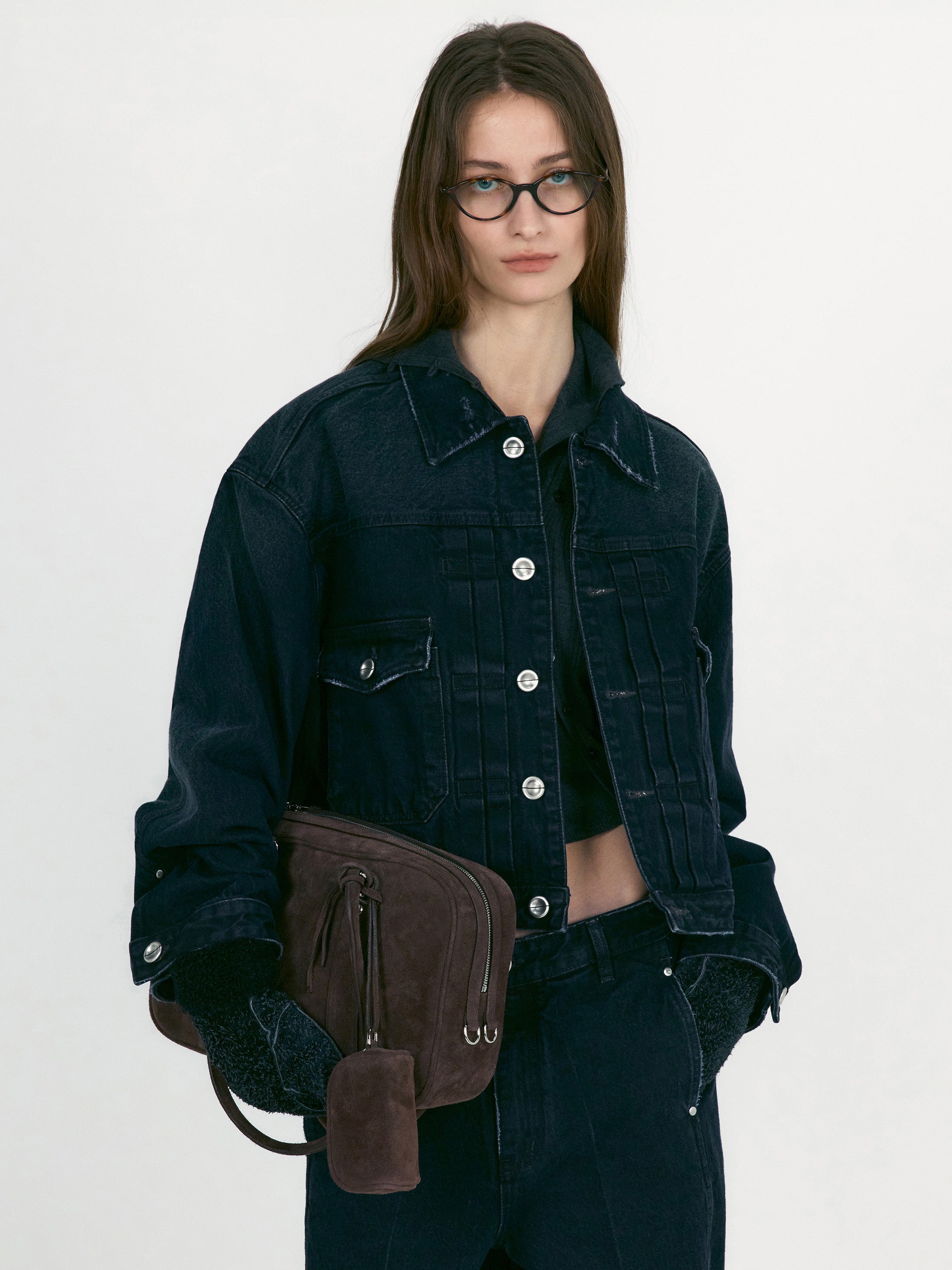 Front view of a woman wearing Low Classic Mahogany Black Denim Short Trucker Jacket featuring silver hardware and a relaxed cropped fit at Alas Eius. 