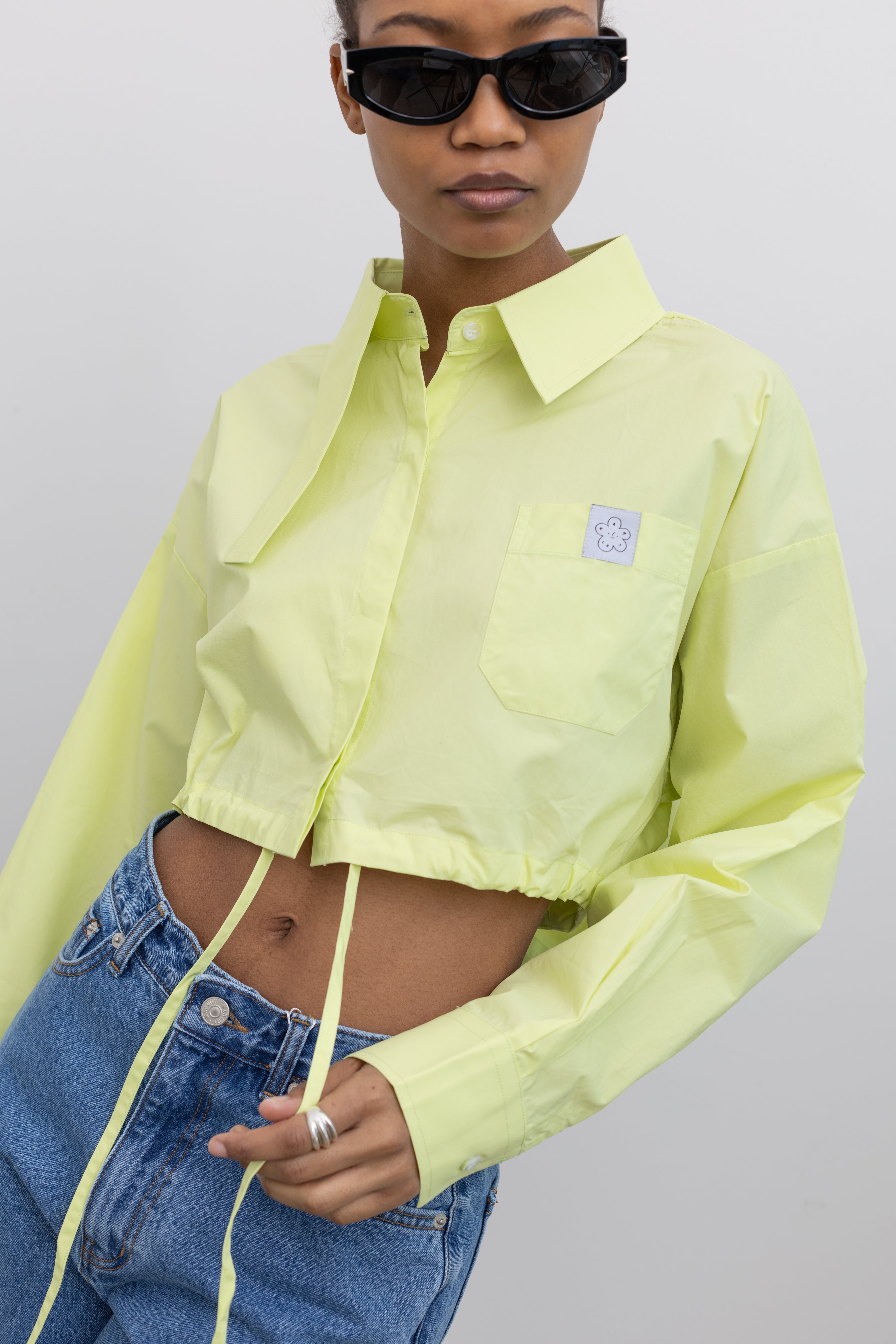Woman wearing Spring fashion in a Mary Lo Citron Long Collar Cropped Button Down Shirt with light wash denim jeans and sunglasses at Alas Eius 
