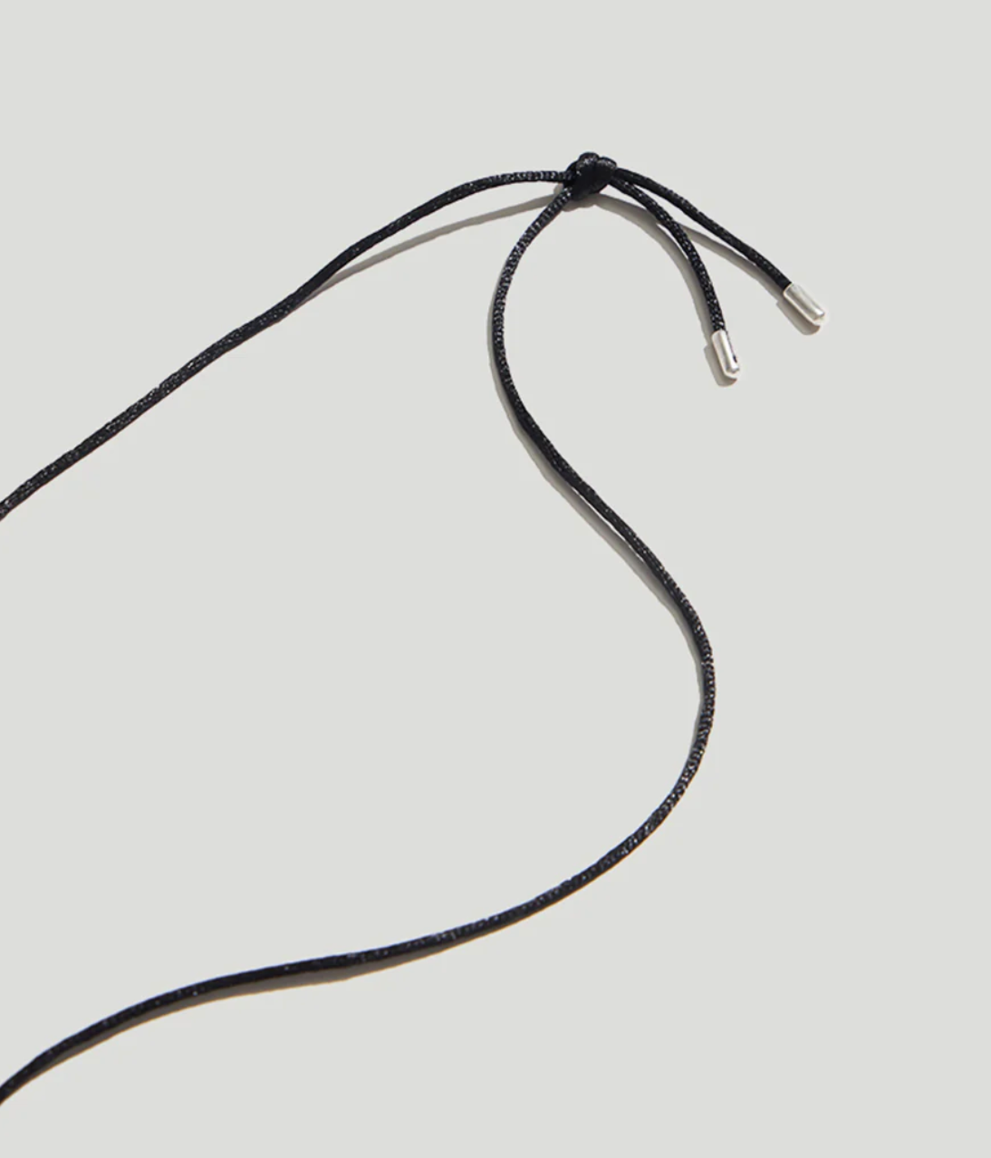 Product view of closure on a contemporary style necklace featuring a sterling silver pendant inspired by a tumbled beach stone on a black silk cord at Alas Eius. 