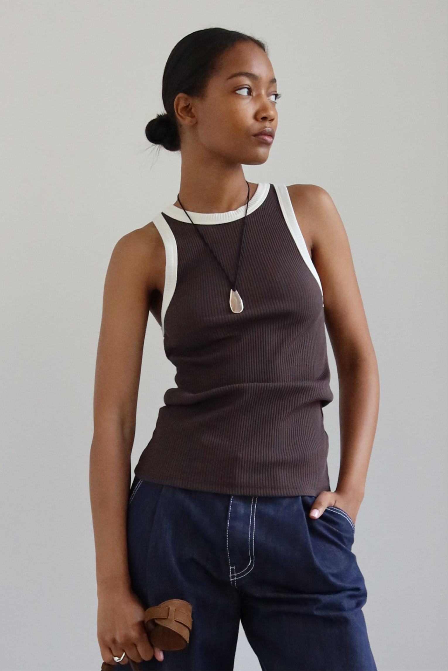 Woman wearing a contemporary style necklace featuring a sterling silver pendant inspired by a tumbled beach stone on a black silk cord at Alas Eius. 