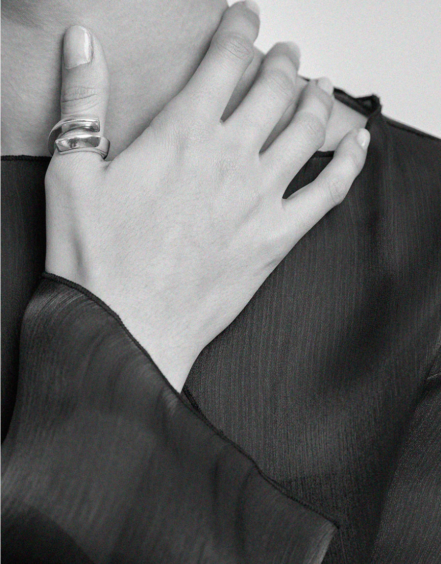 Woman wearing a minimalist sterling silver wrap ring on her thumb by Maslo at Alas Eius. 