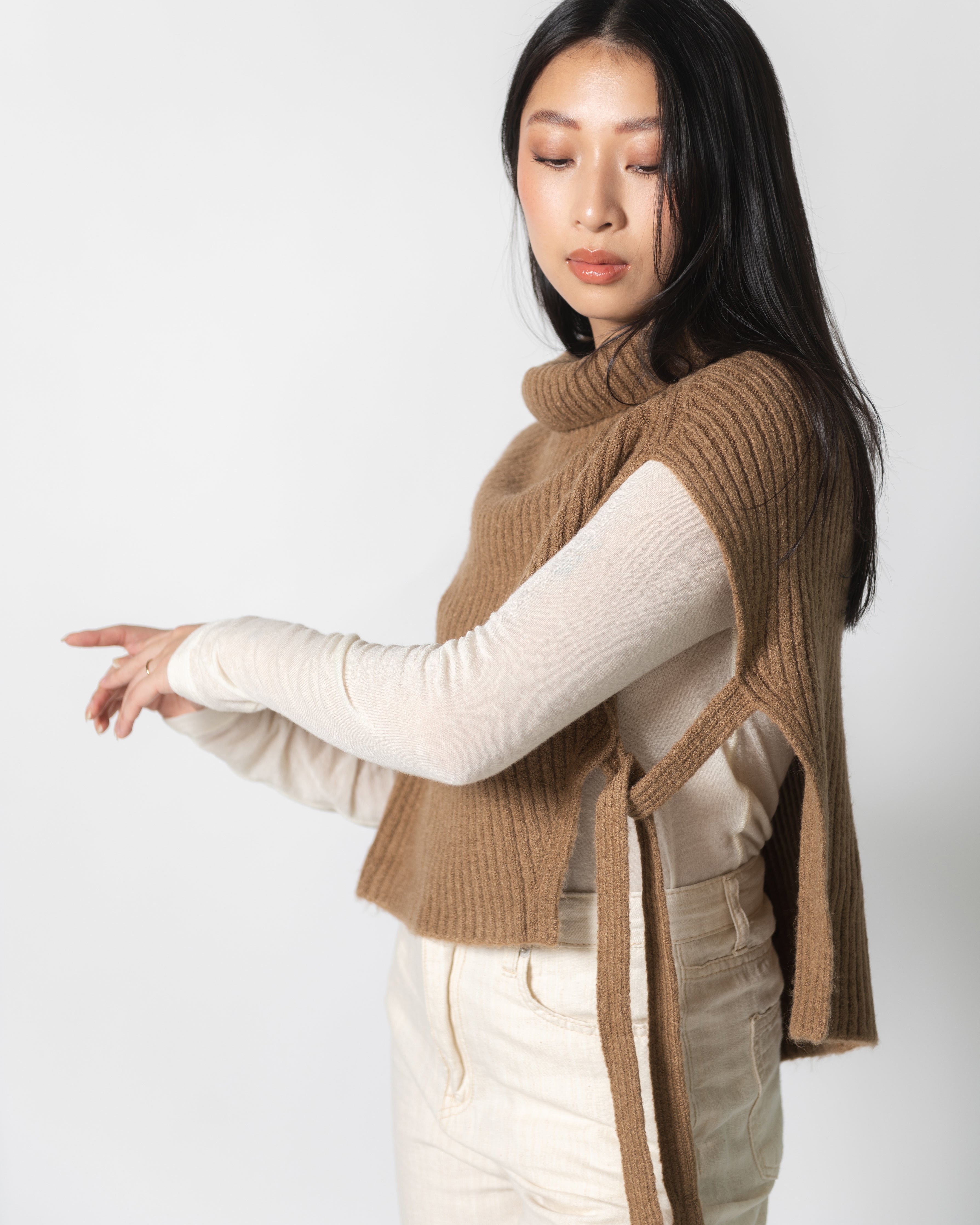 A woman wearing a brown ribbed neck warmer over a white top, paired with beige pants.
